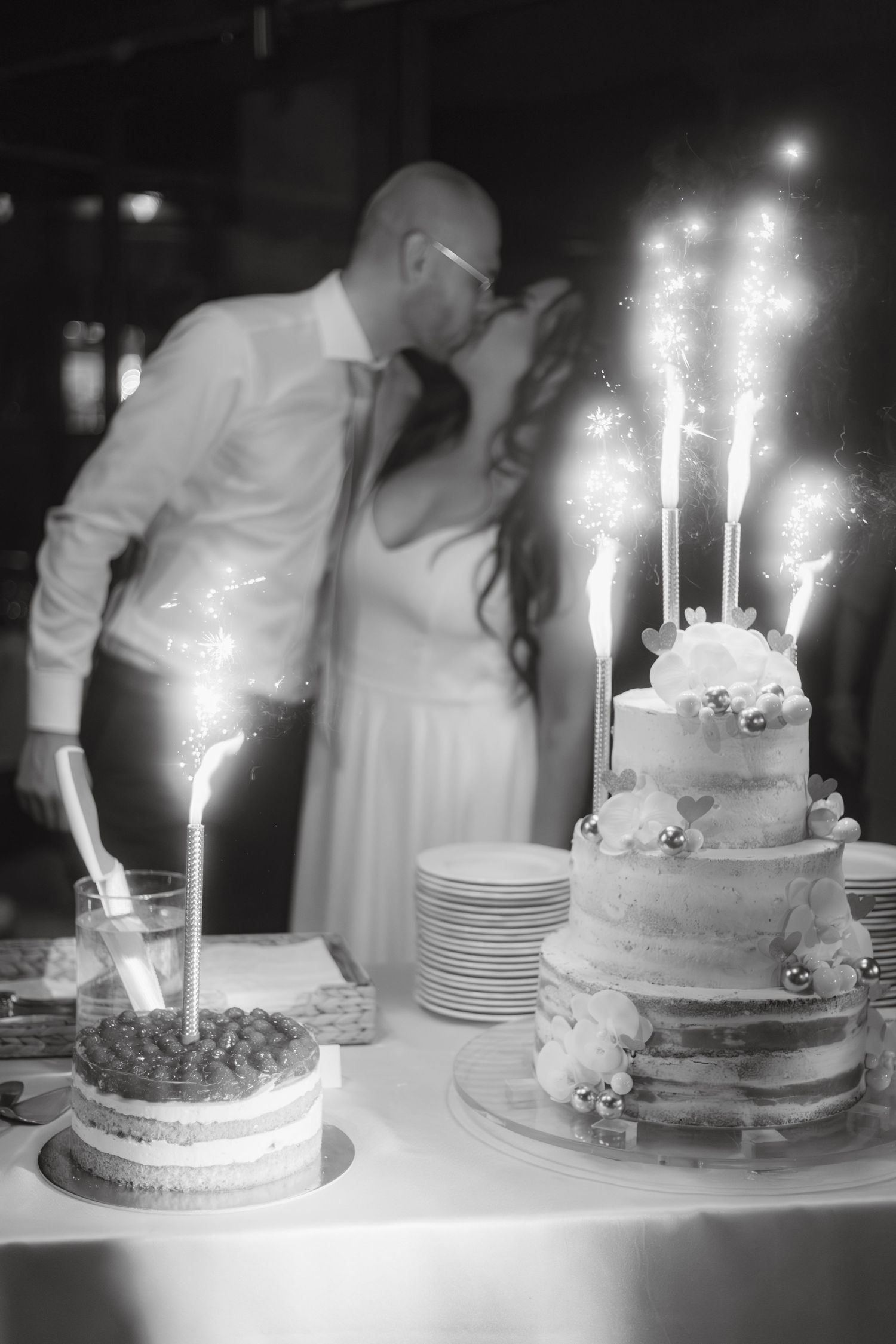 Wedding cake with sparklers creating dramatic lighting effect at reception.