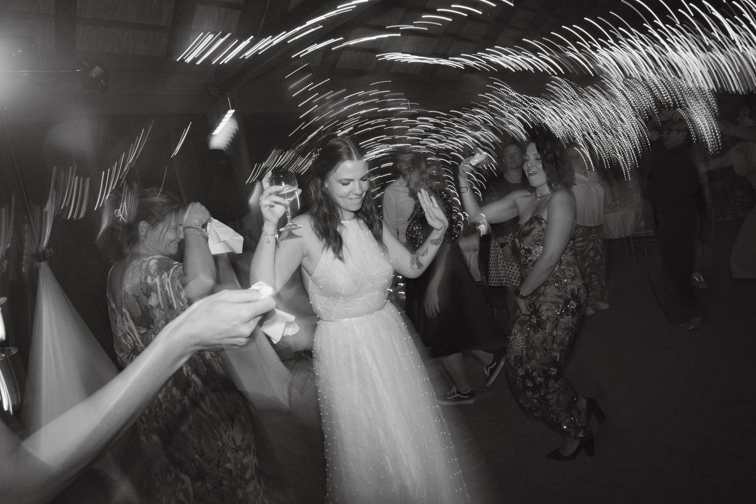 Silhouettes of people dancing under palm fronds at a nighttime celebration.