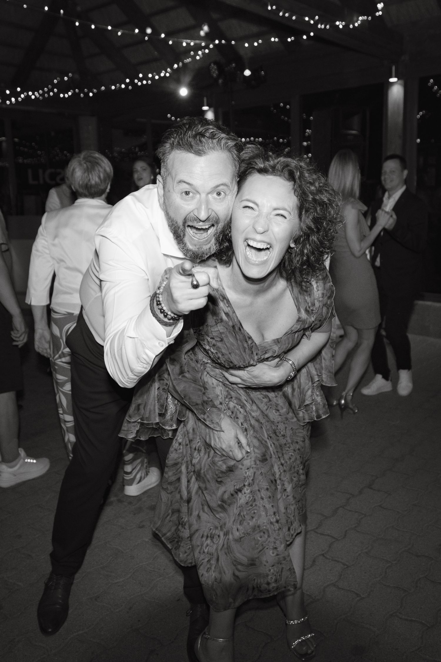 Black and white photo sequence showing a joyful dance moment at a party with string lights in the background.