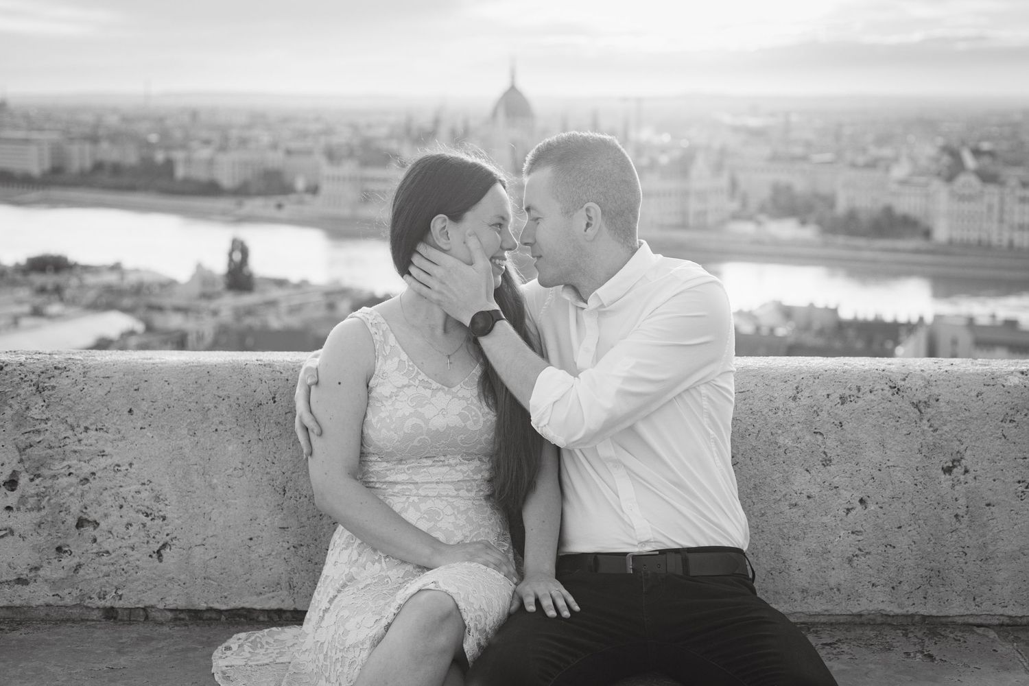 A romantic black and white photograph of a couple sharing an intimate moment overlooking a scenic cityscape in Italy.