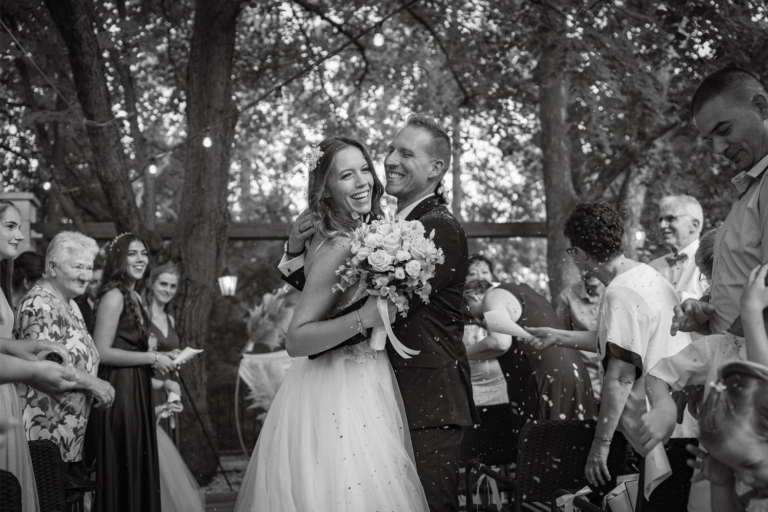 Black and white candid photos capturing joyful moments at an outdoor wedding celebration.