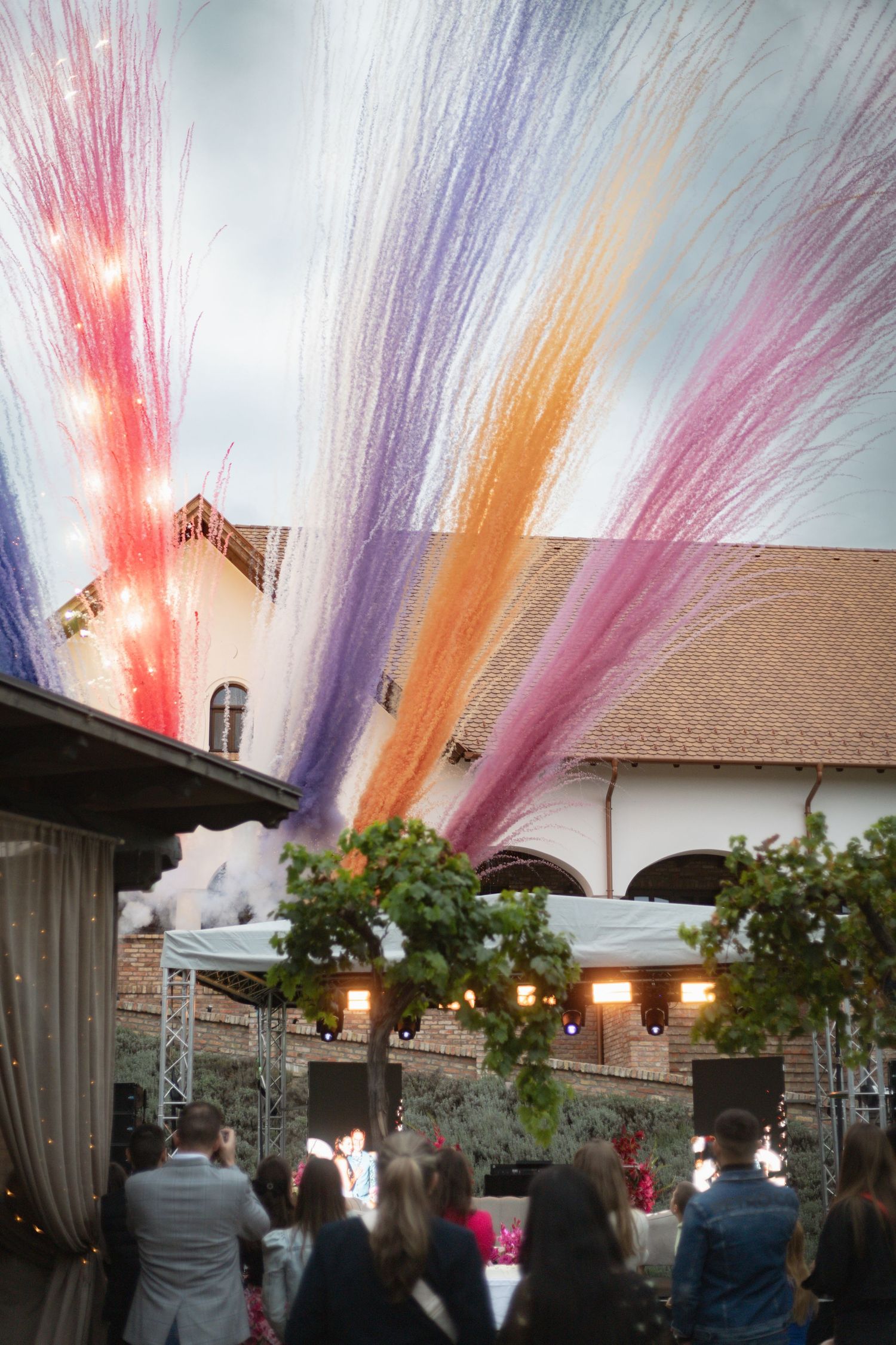 Colorful streamers create a vibrant canopy over an outdoor event venue at dusk.