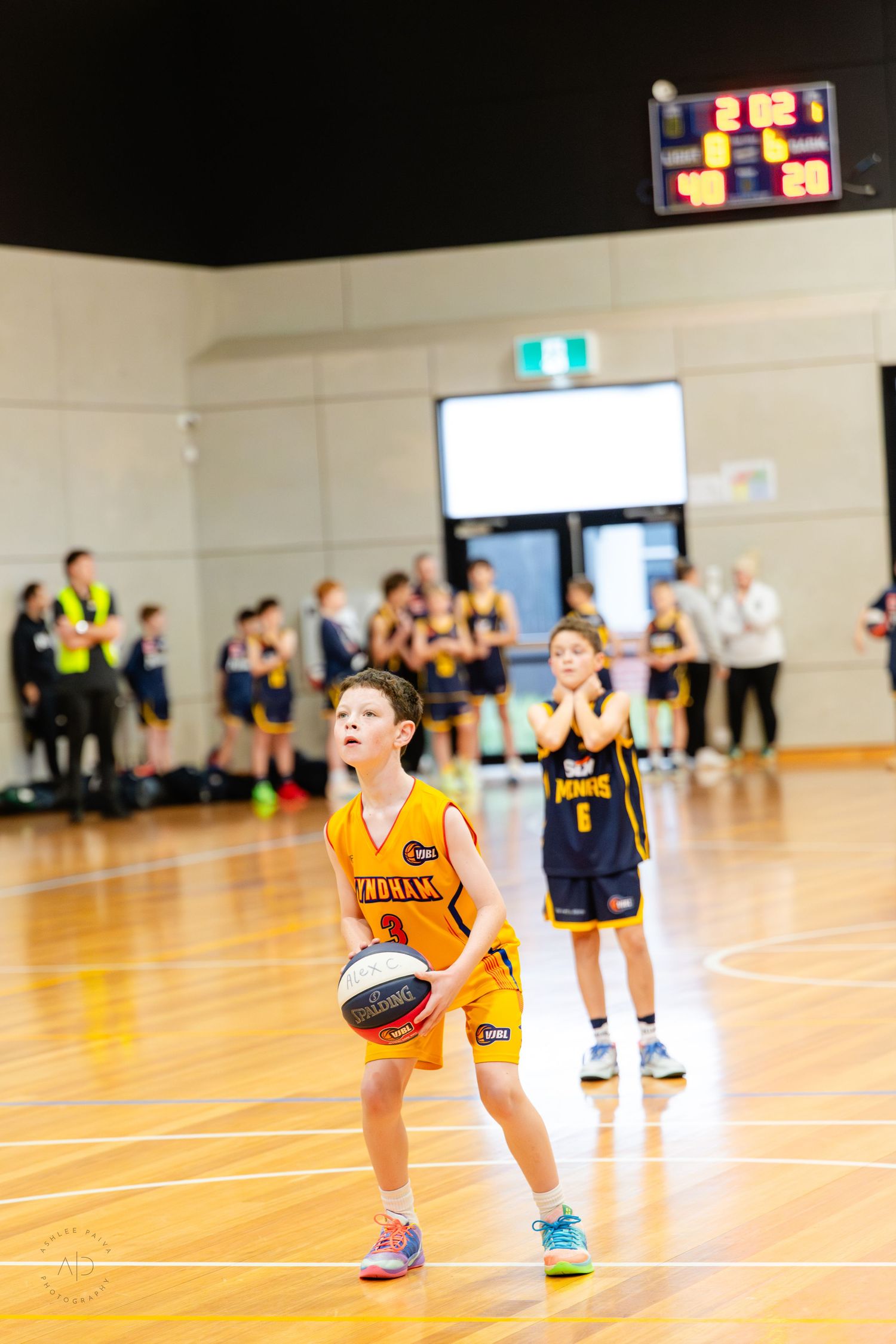 Young boy in yellow jersey prepares to shoot a free throw during a youth basketball game indoors.