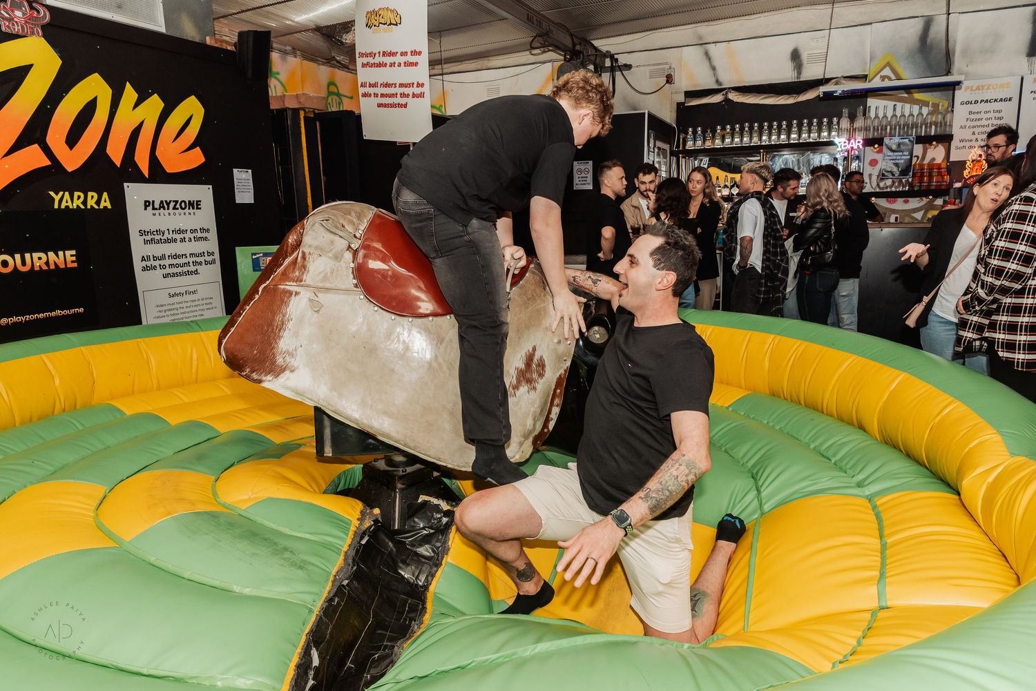 Two men on a mechanical bull ride at Flatzone Yarra Melbourne indoor entertainment venue.