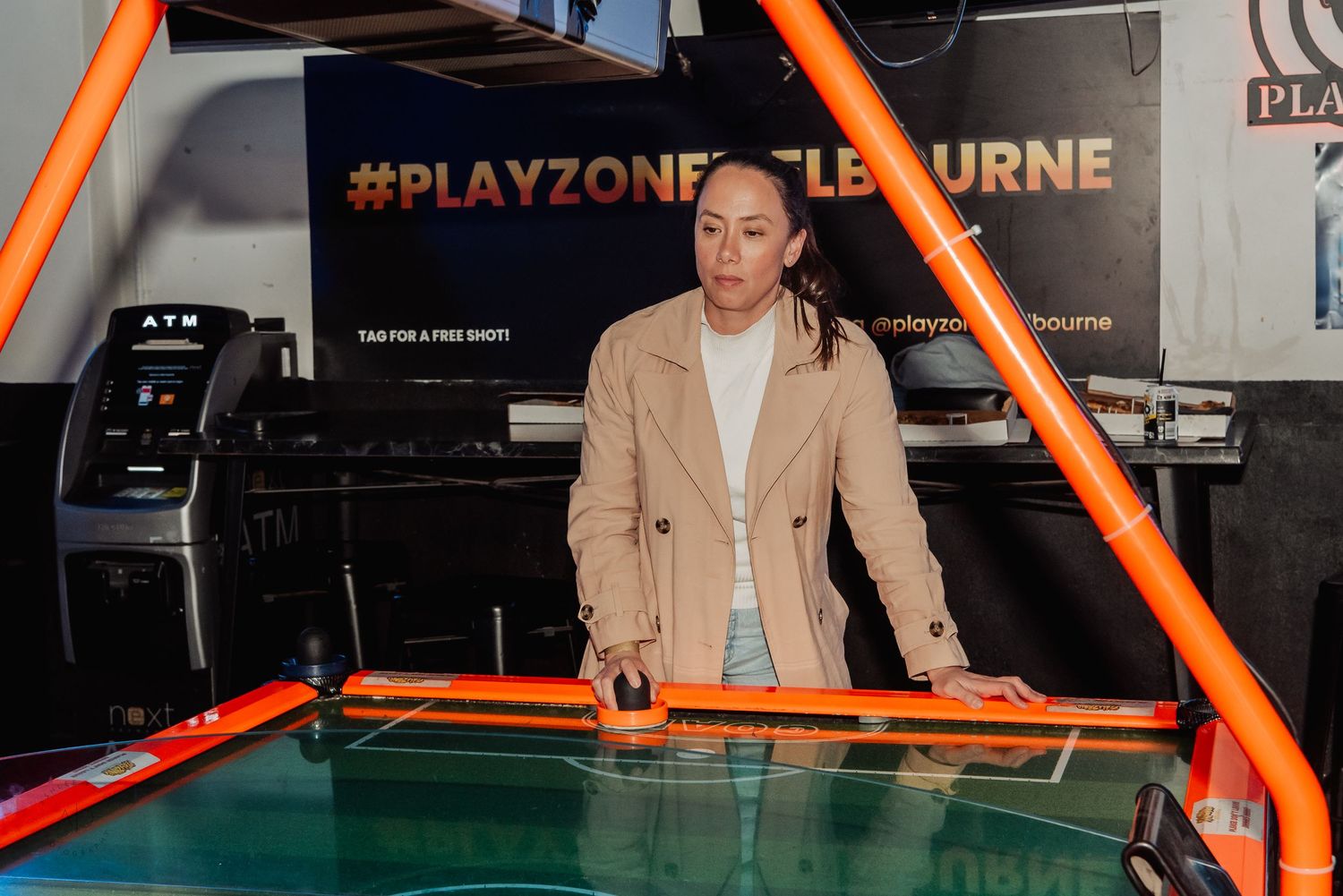 Woman playing air hockey at PlayZone Melbourne arcade entertainment venue.