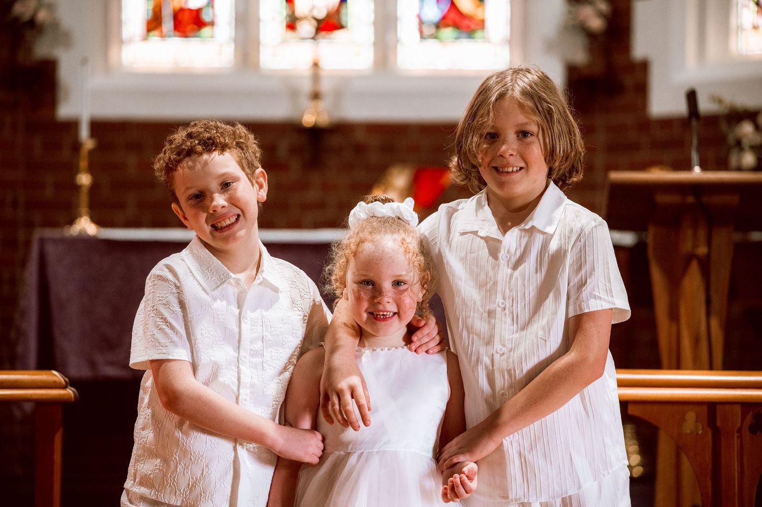 Group of people in white clothing gathered inside traditional church setting.