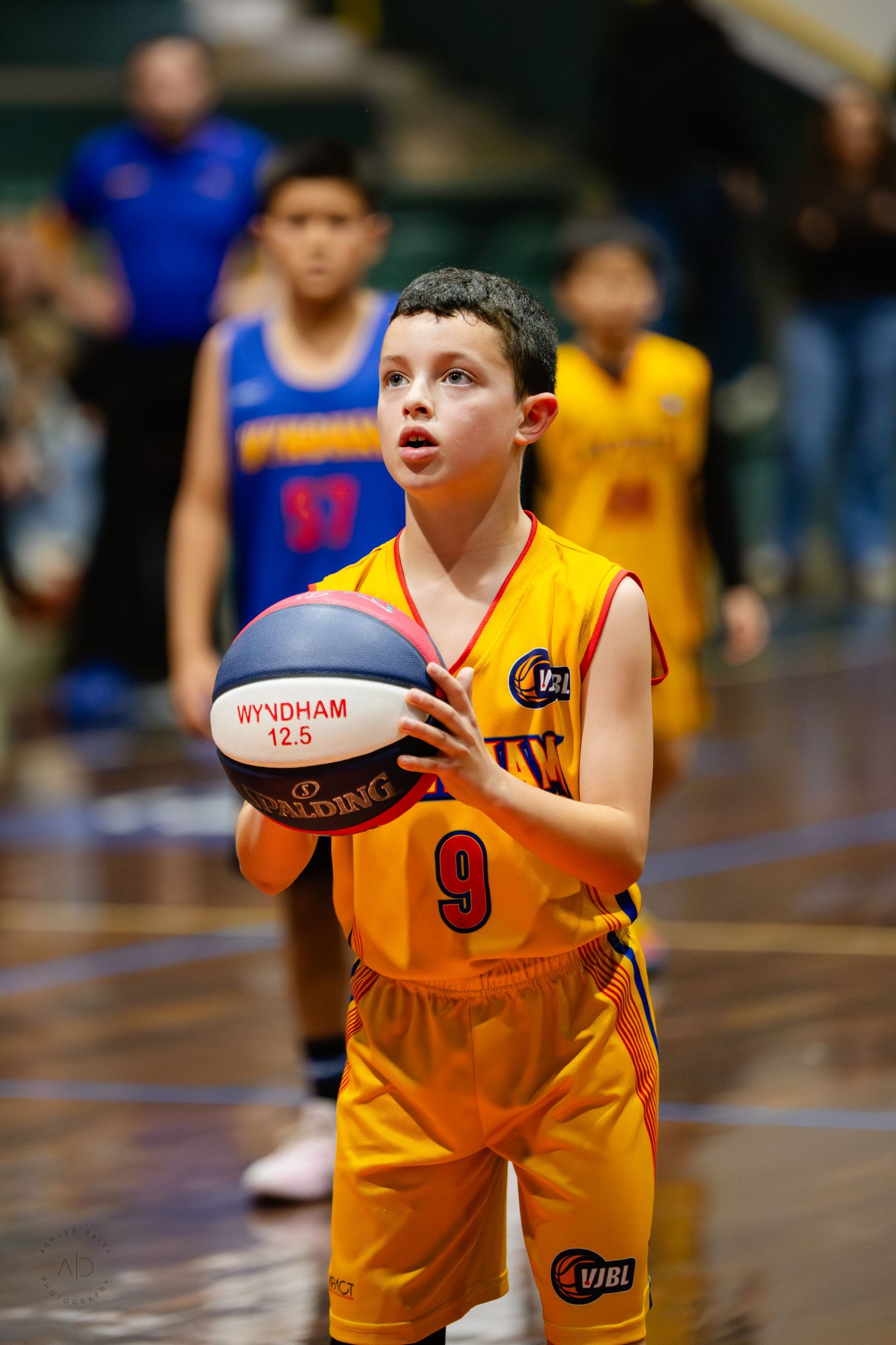 Young boy in yellow jersey #9 prepares to shoot a basketball during a youth VJBL league game.