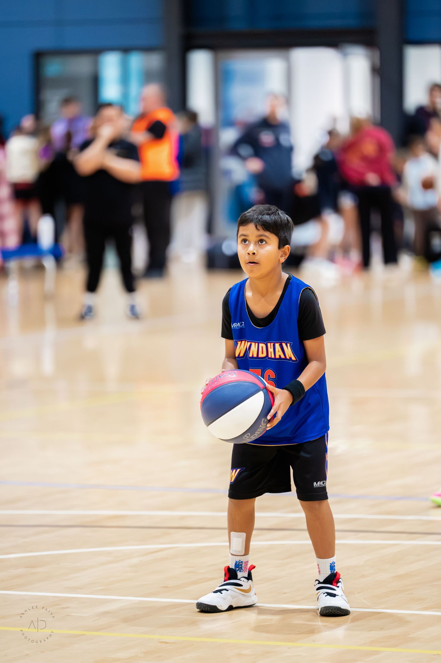 Young boy in Wyndham basketball jersey holding a ball on an indoor court during a youth basketball game.