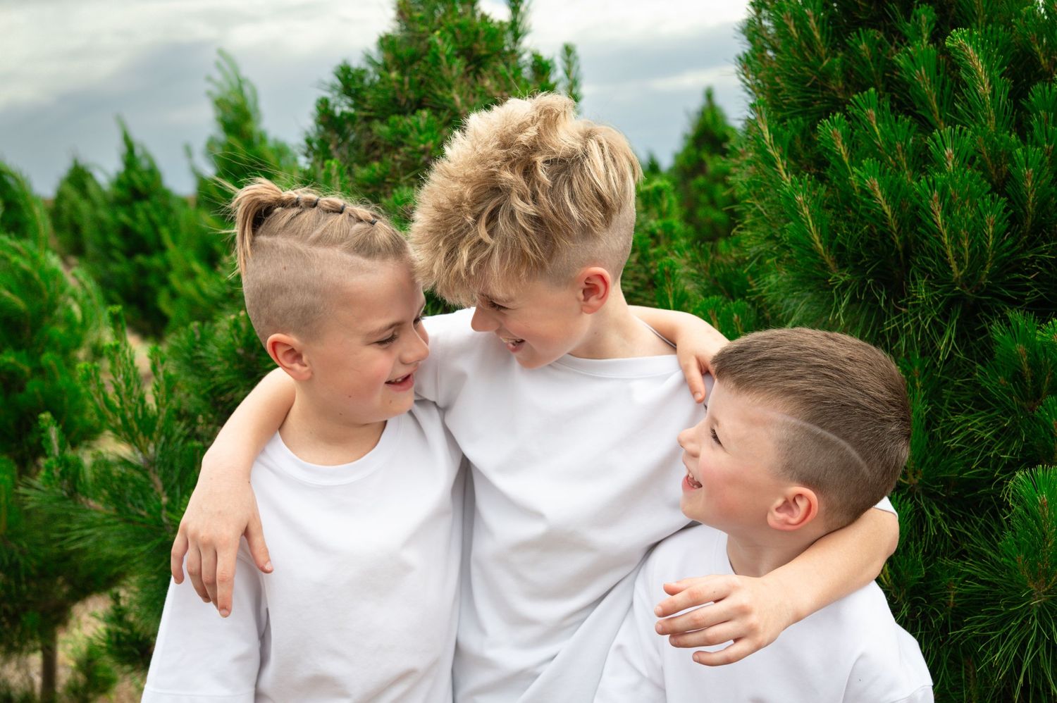 People in white shirts walking together between rows of pine trees.