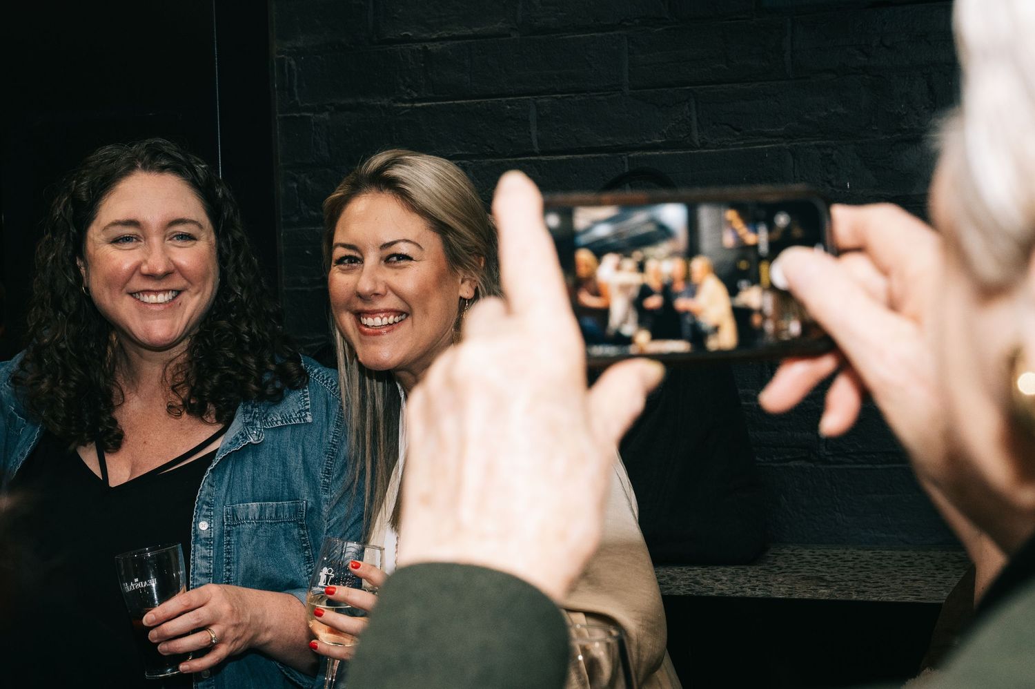 Guests laughing while someone takes their photo at a social gathering.