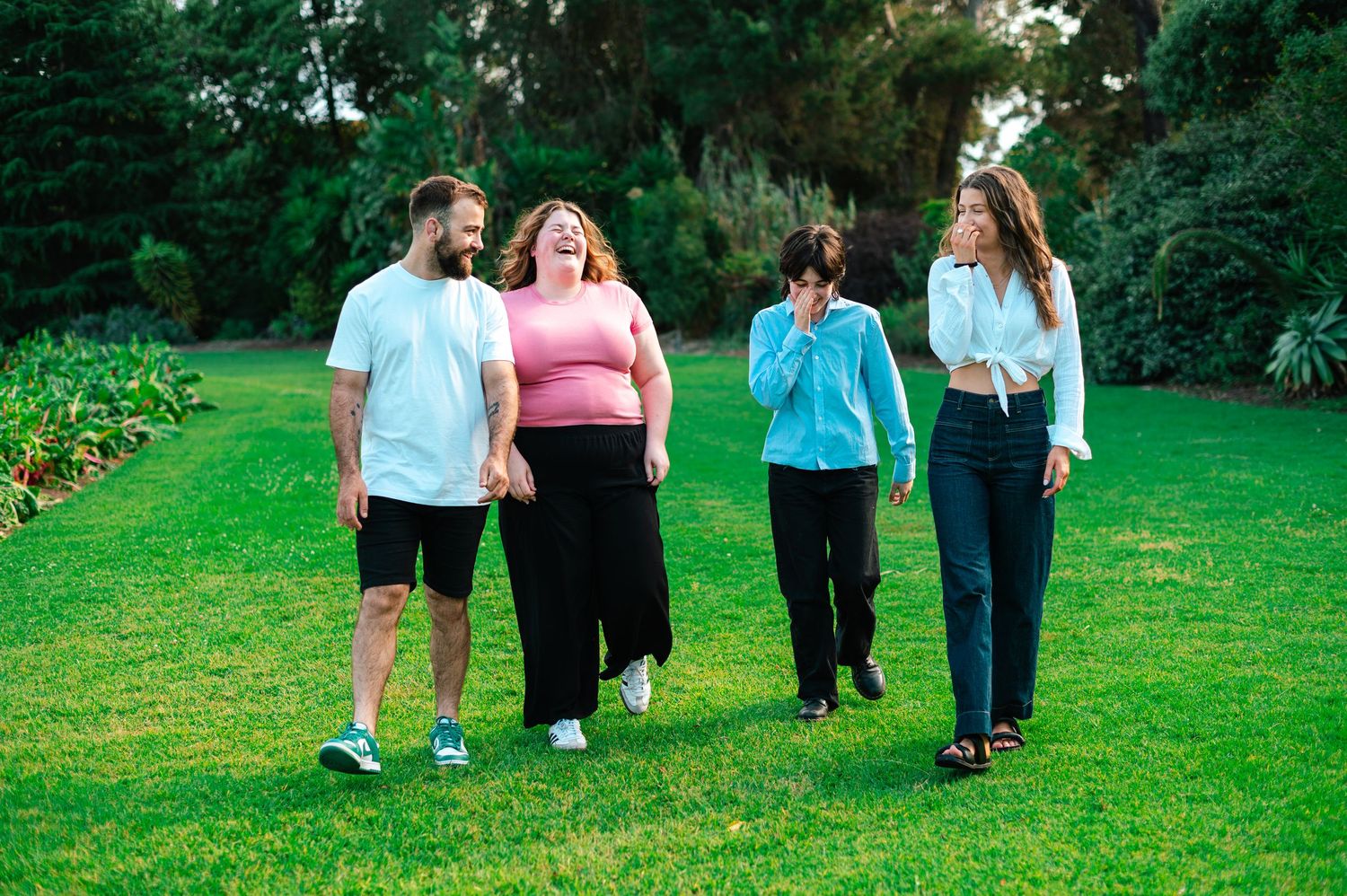Group walking together across a green lawn during a casual outdoor photoshoot.