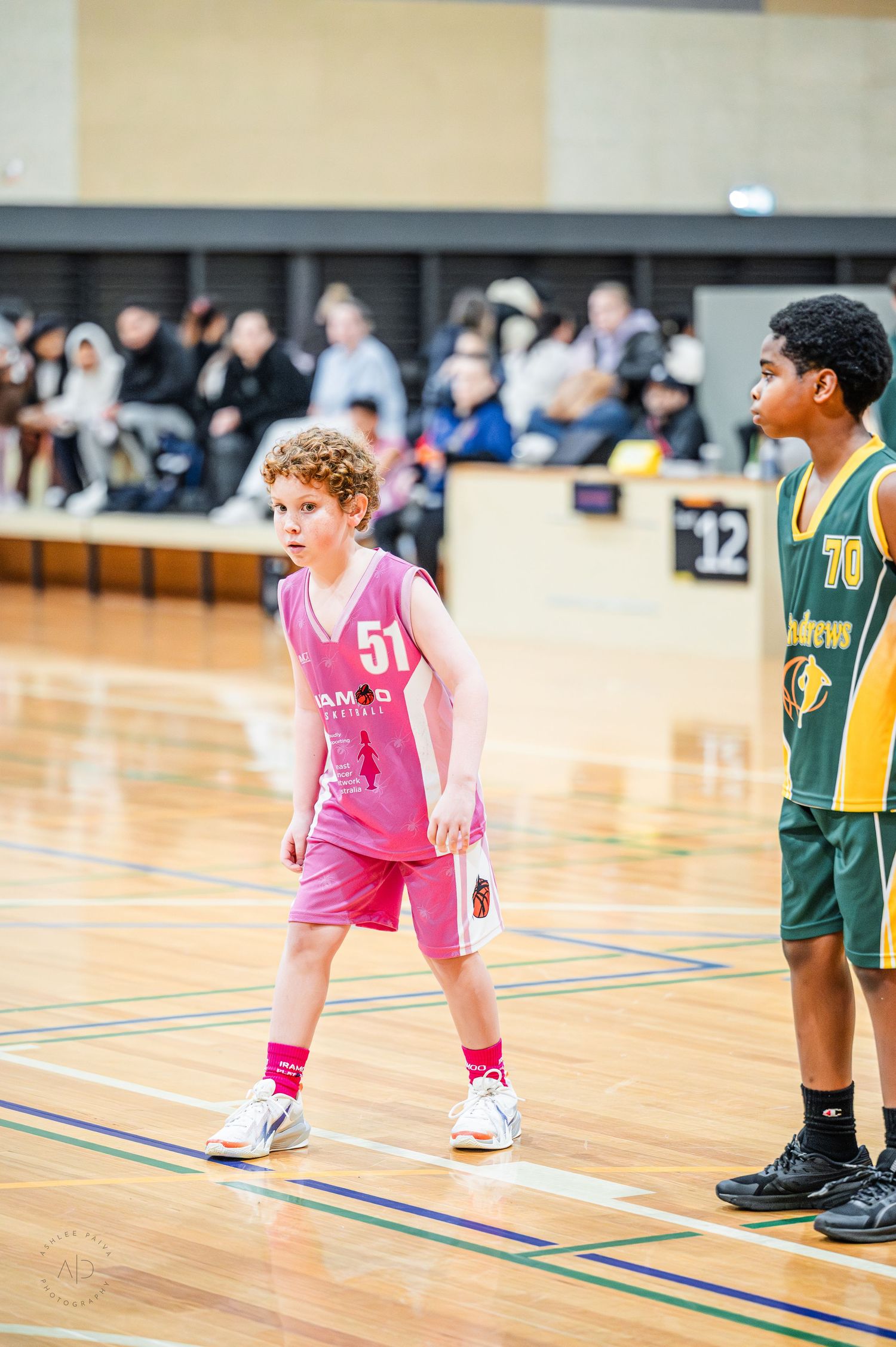 Young boy in pink #51 basketball uniform plays in indoor youth basketball game against green team.