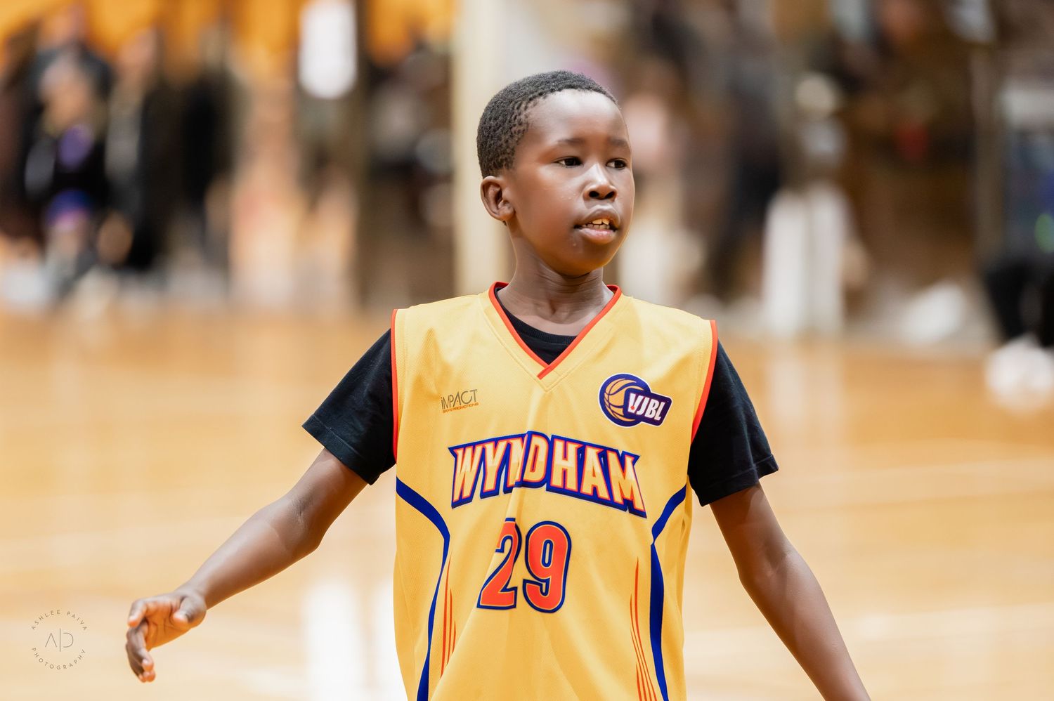 Young basketball player wearing Wyndham number 29 yellow jersey on an indoor court.