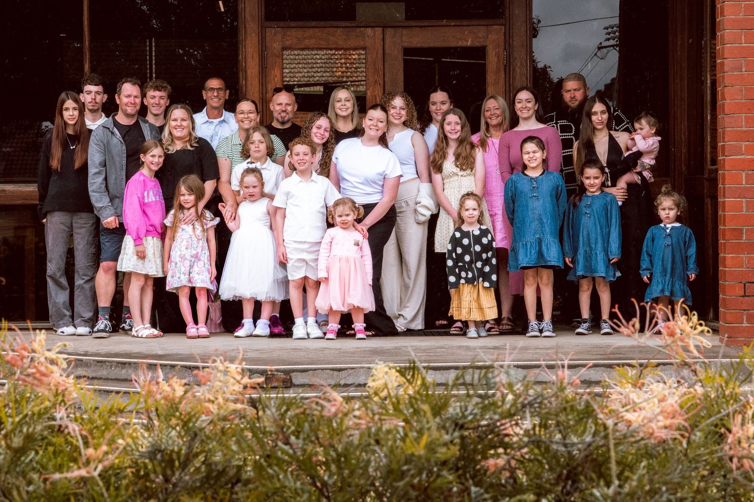 Large group photo of congregation members standing outside brick church building.
