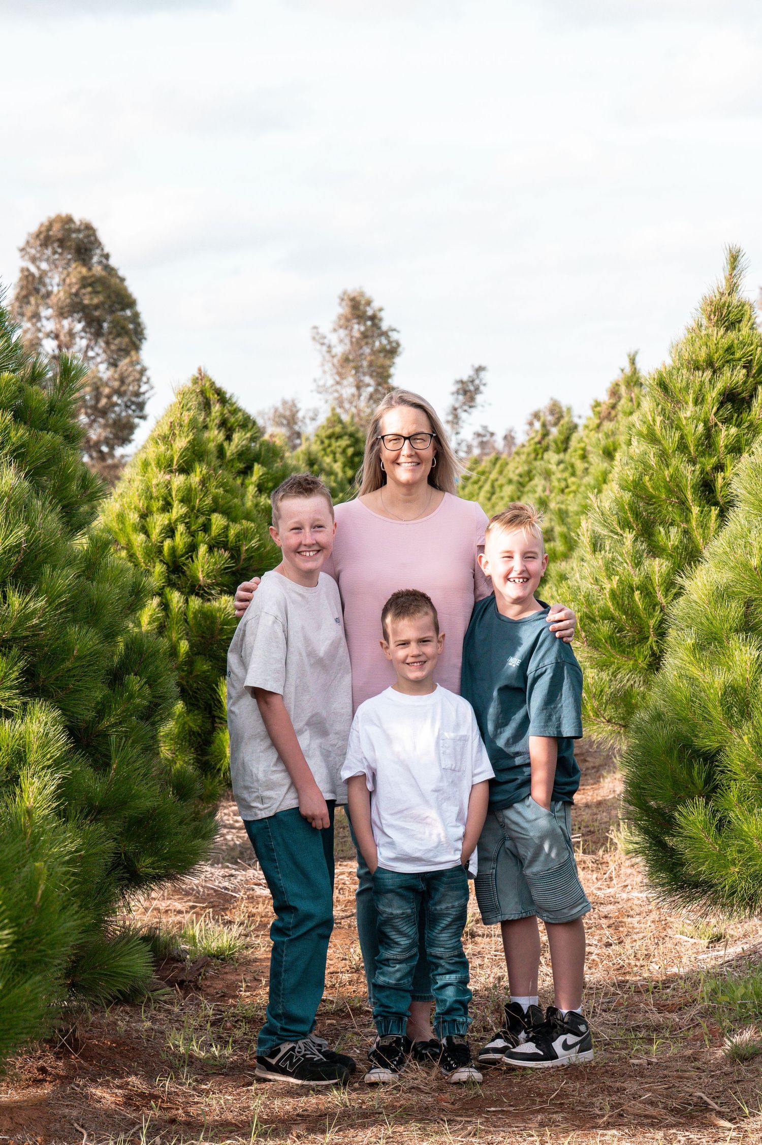 Group photo taken at Christmas tree farm with evergreen trees surrounding them.