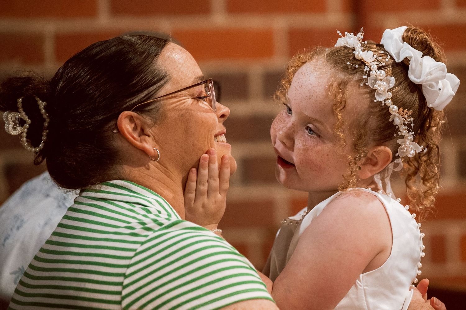 A touching moment between two people against a brick wall background.