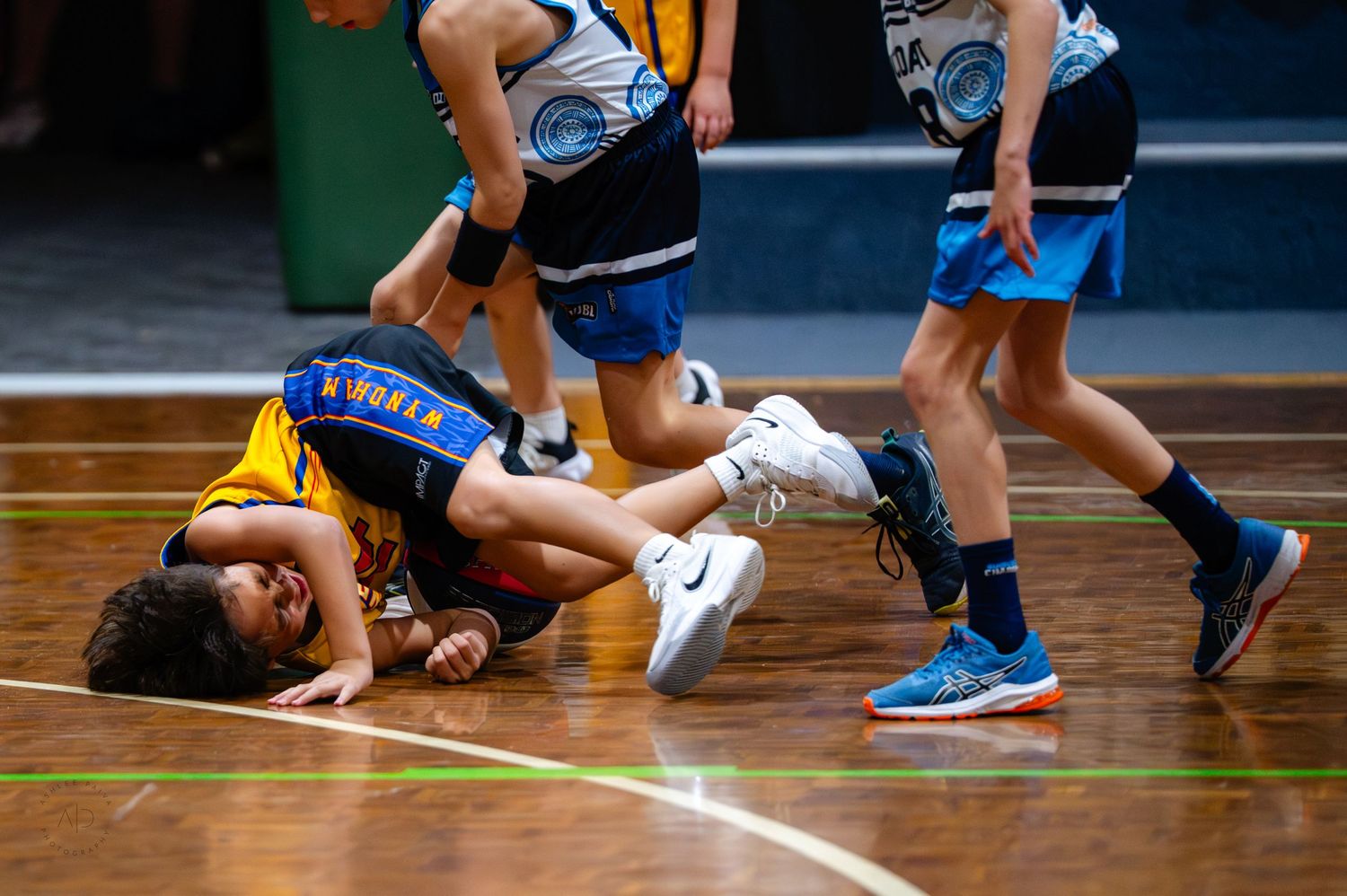 Young basketball players scramble for the ball on an indoor court during an intense youth league game.