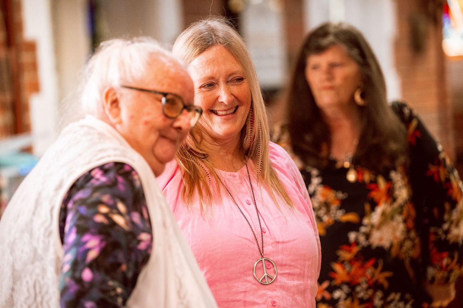 People gathered in a church wearing festive clothing and smiling.
