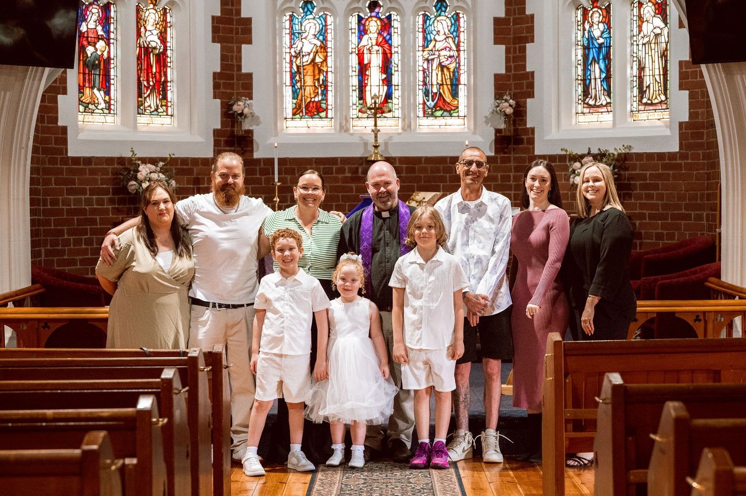 Group photo inside a church with stained glass windows and brick walls.