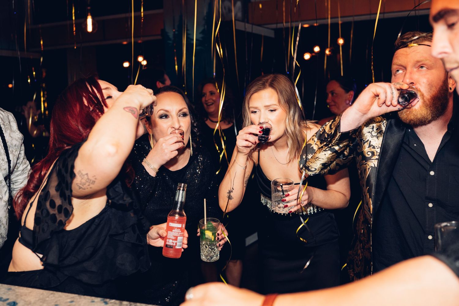 Party guests take shots and drinks together at a lively celebration.
