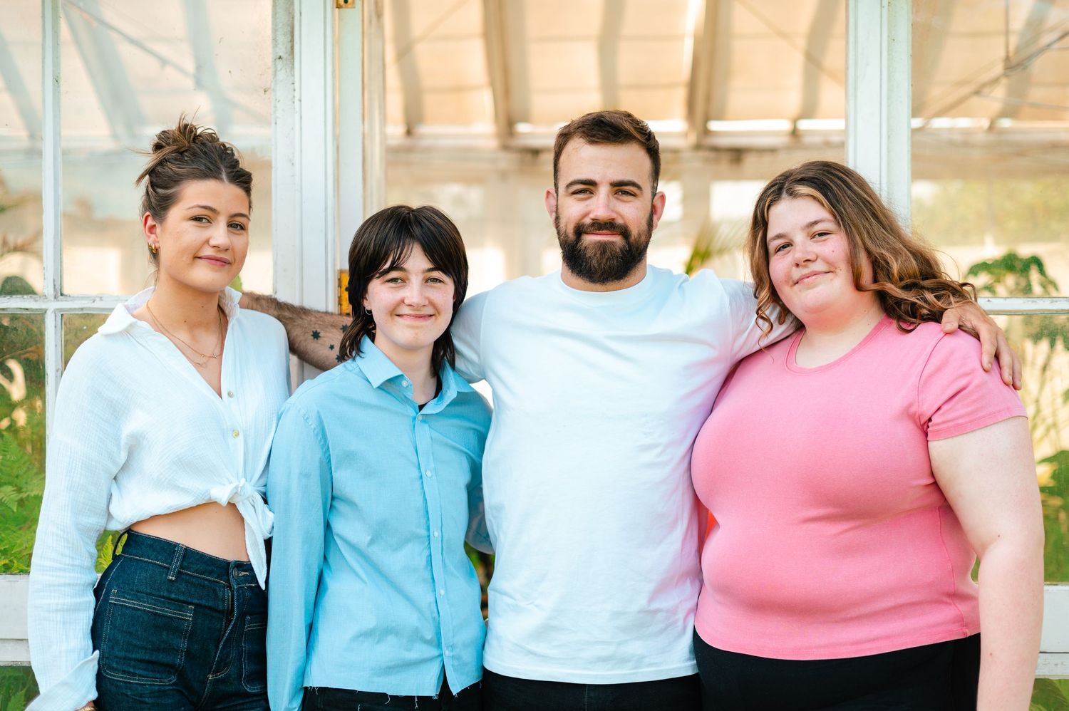 Group portrait against a white architectural backdrop wearing coordinated casual outfits.