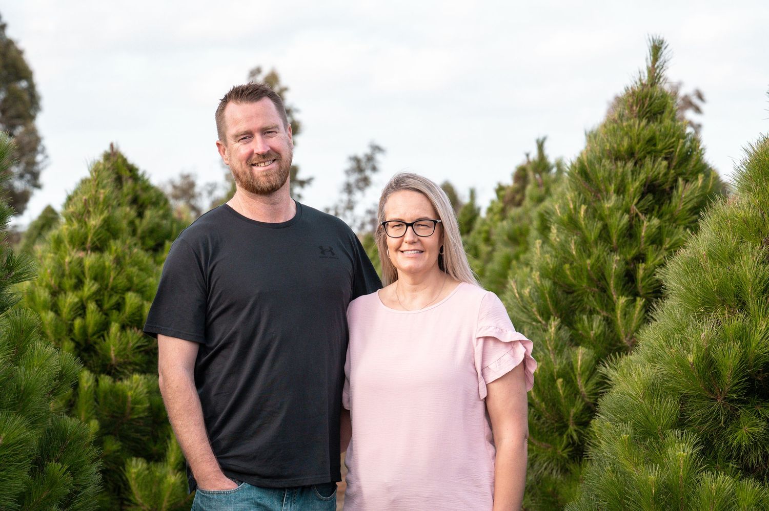 Group portrait taken at a Christmas tree farm with pine trees in background.