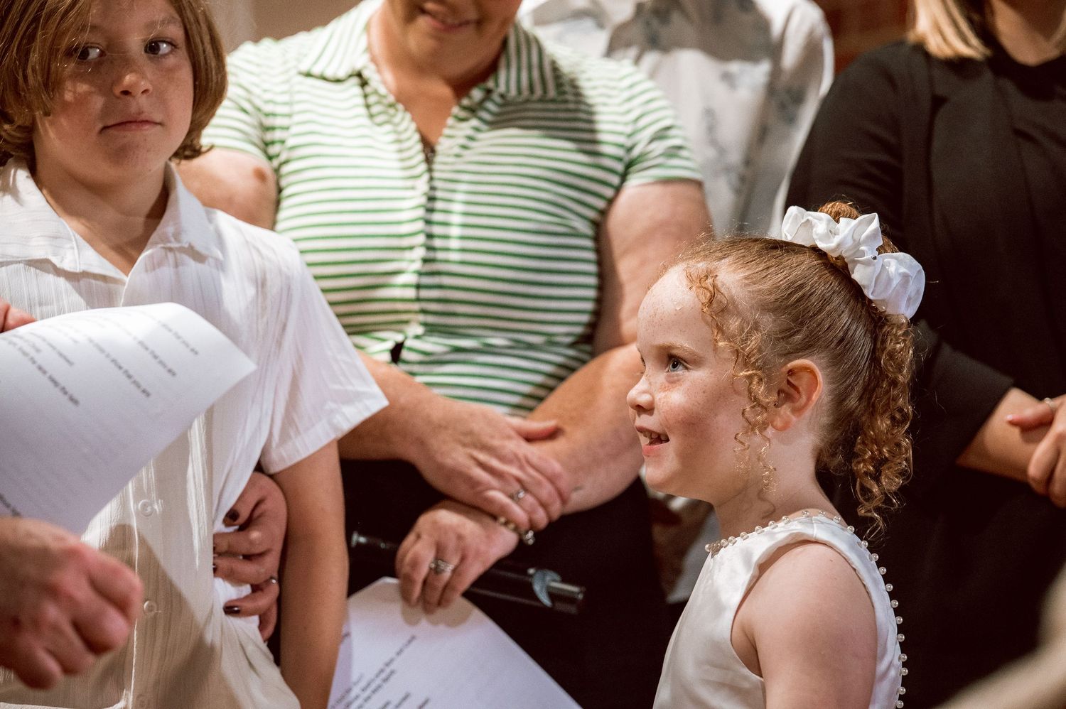 A child in a white dress with a bow participates in a church ceremony.