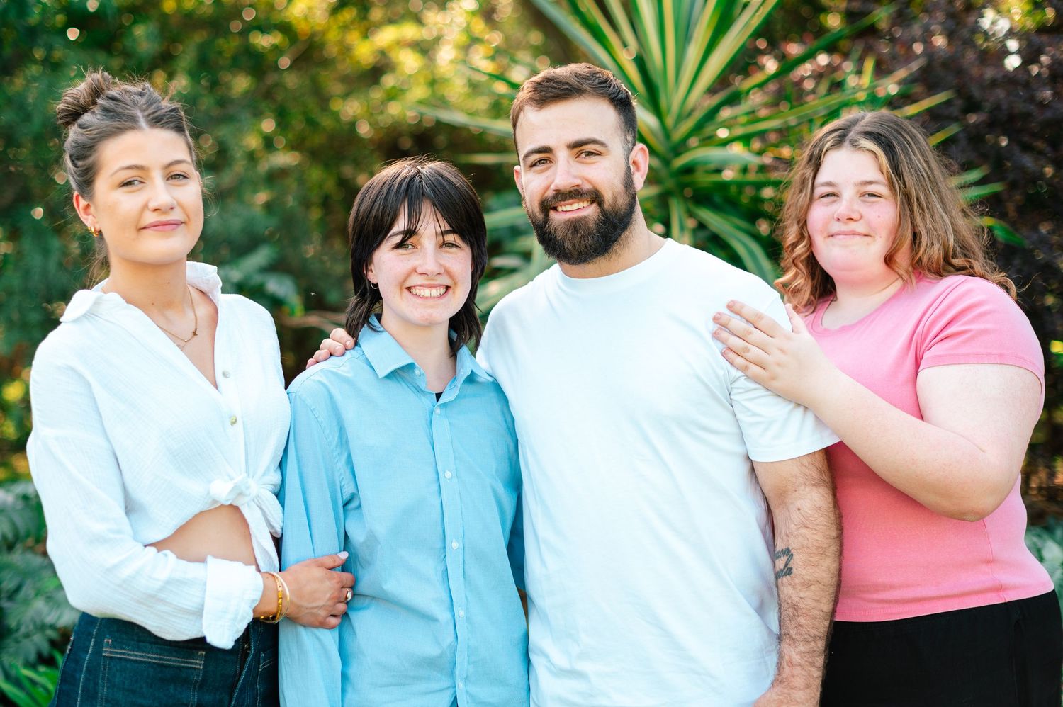 Friends gather for a casual outdoor photoshoot in coordinated blue and pink outfits.