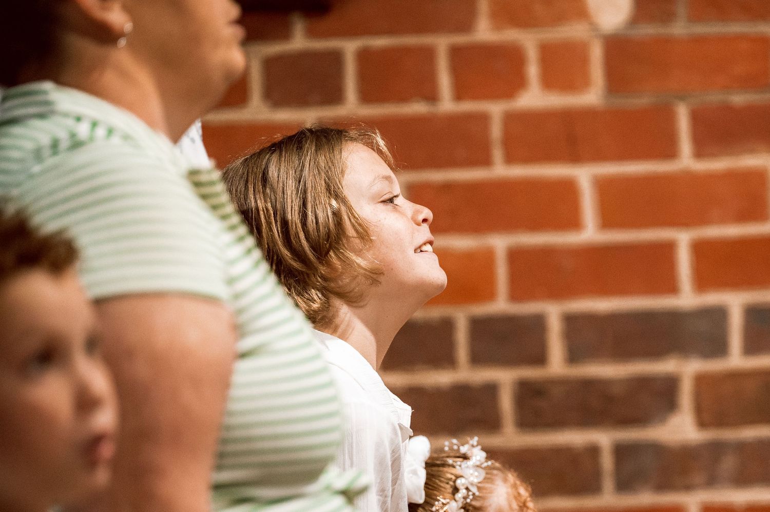 Candid moments captured during church gathering against brick wall.