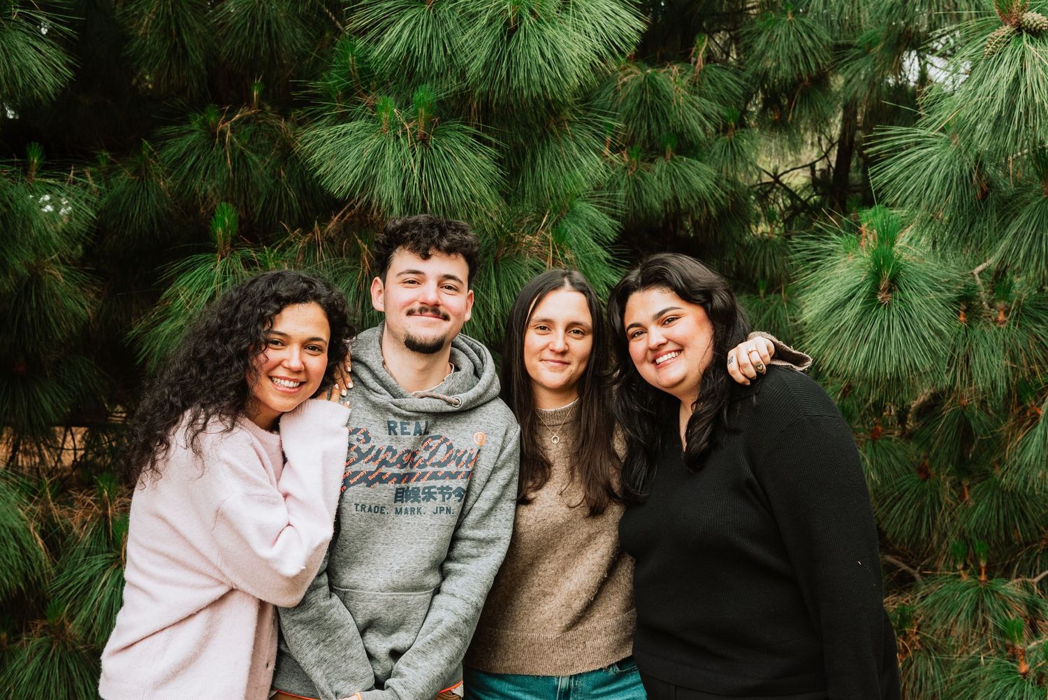 Group portrait against a backdrop of evergreen pine trees.