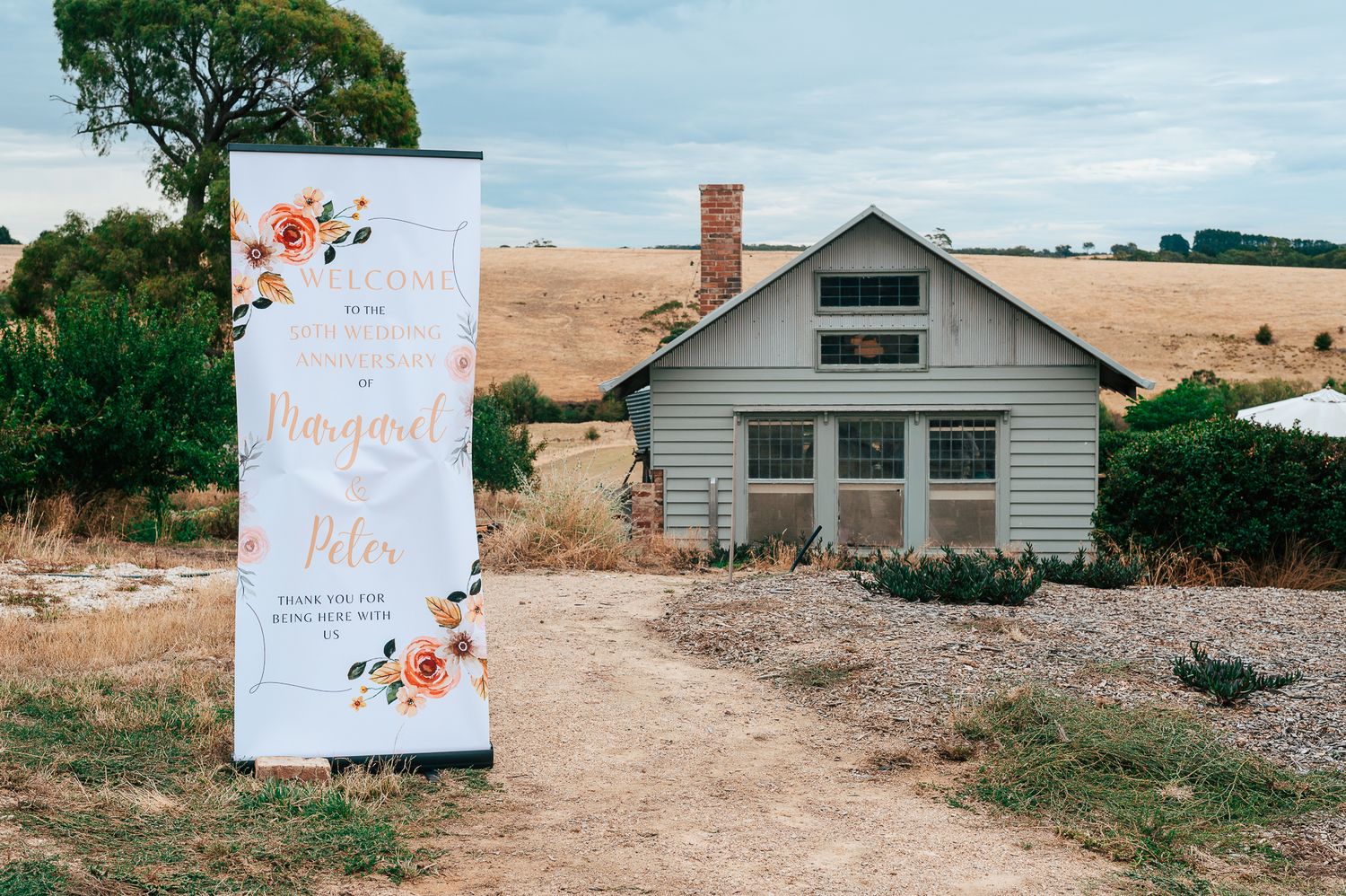 A panoramic collage of rustic farmhouse buildings with decorative signs in a rural landscape setting.
