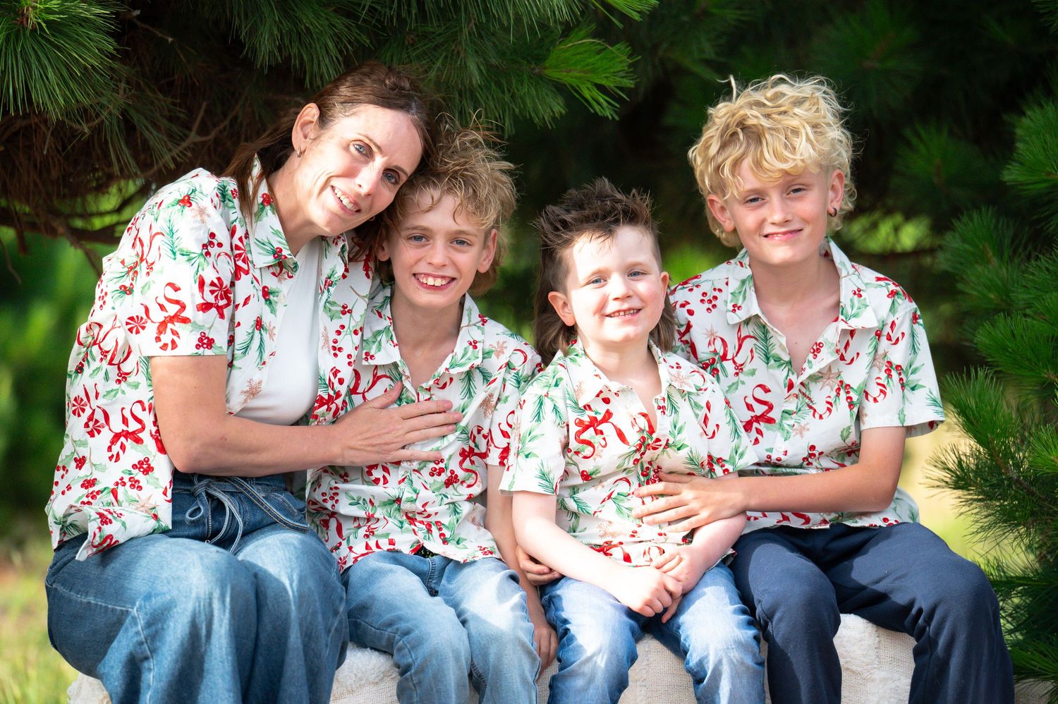 Family group photo with coordinated floral shirts against lush green background.