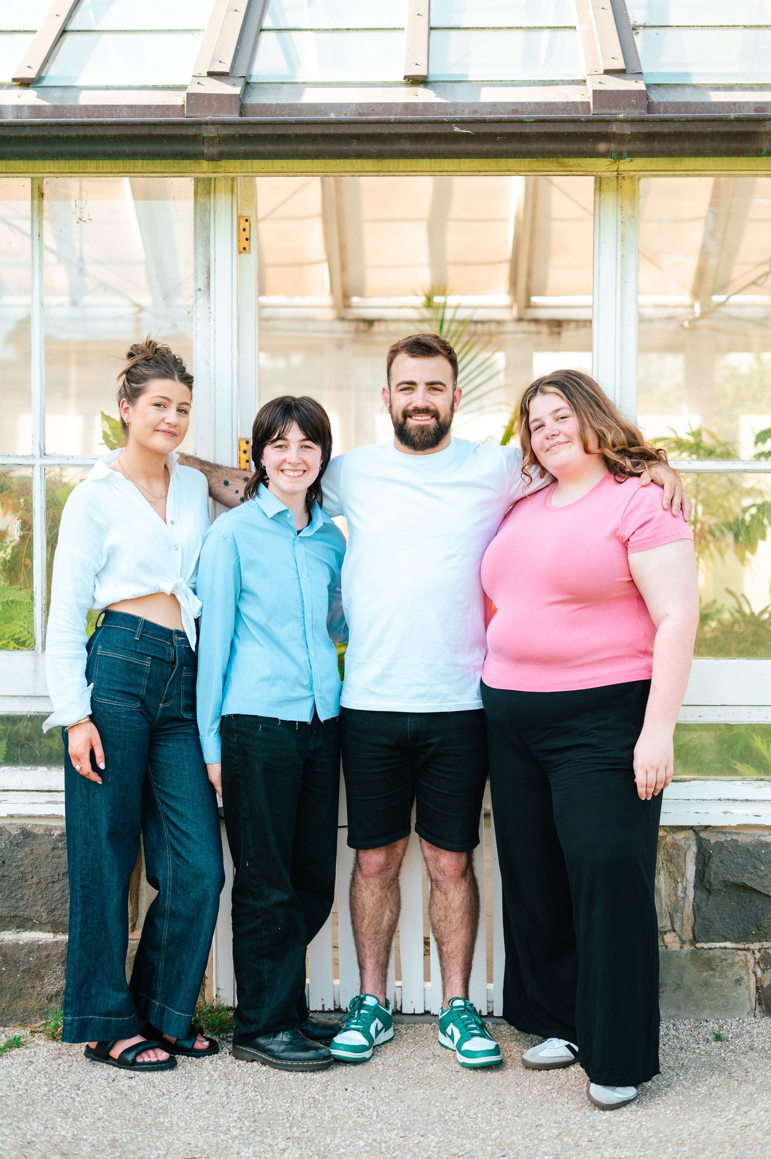 Casual group photo against a white building exterior showing full-length view of coordinated outfits.