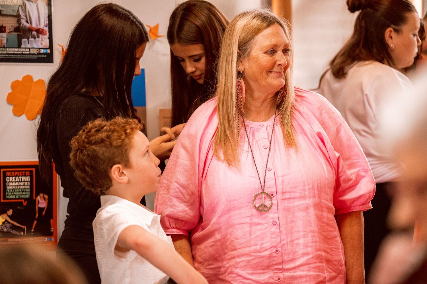 Children and adults gather in a church setting wearing pink and white clothing.