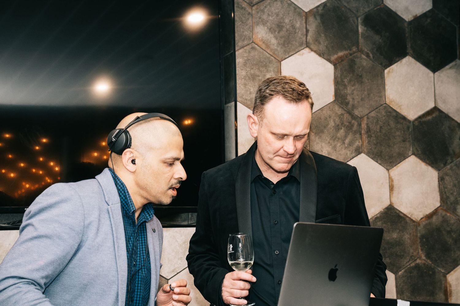 People socializing at a modern venue with hexagonal wall tiles.