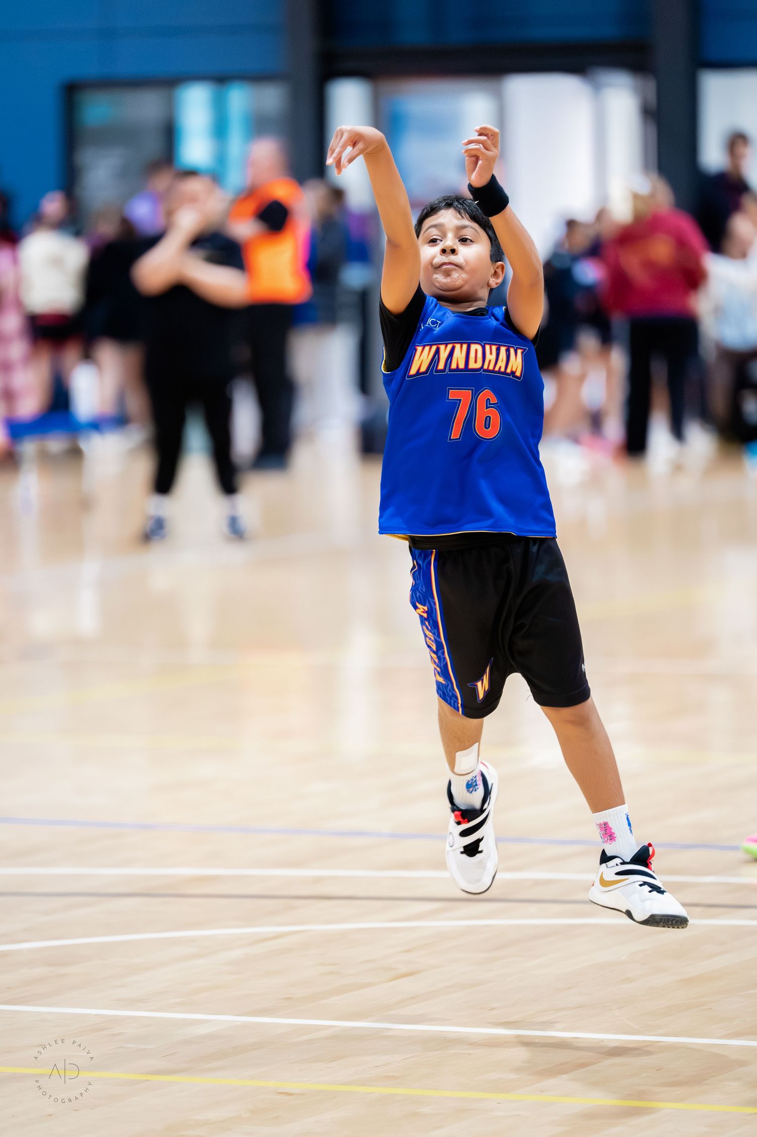 Young basketball player wearing Wyndham jersey number 76 jumping to shoot during an indoor game.