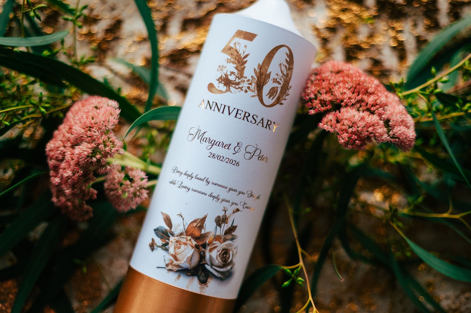 White skincare bottle with gold 30th anniversary design displayed among pink sedum flowers and autumn foliage.