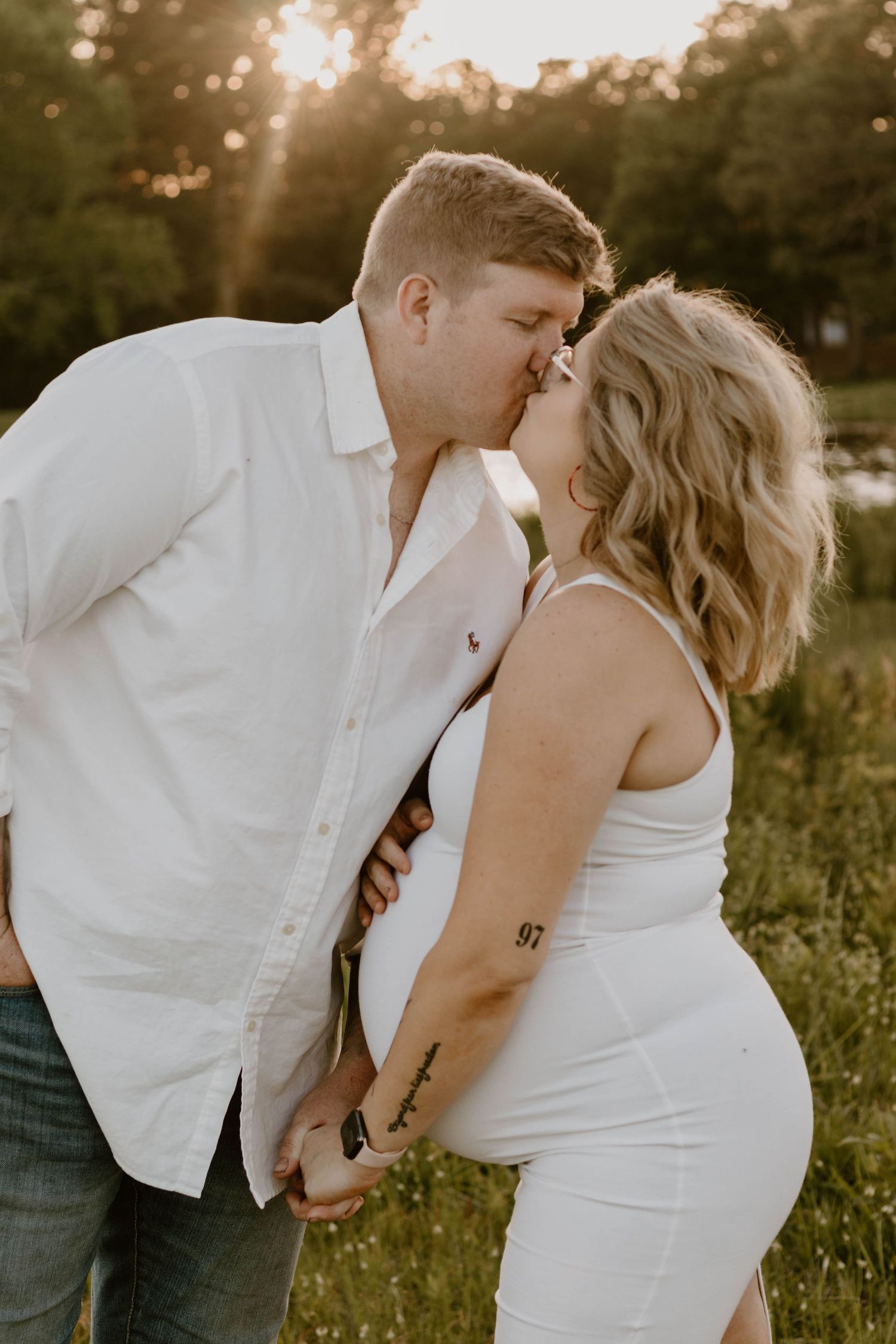 A tender kiss shared between a couple during their maternity photoshoot at sunset.