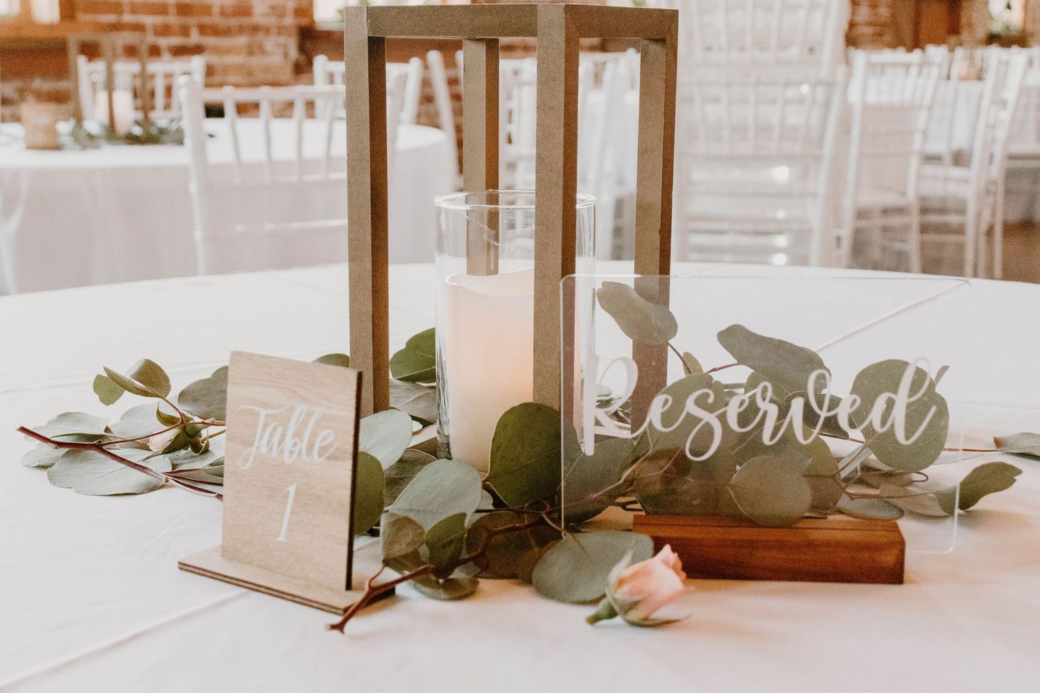 Wedding reception table settings with lanterns and reserved signs.
