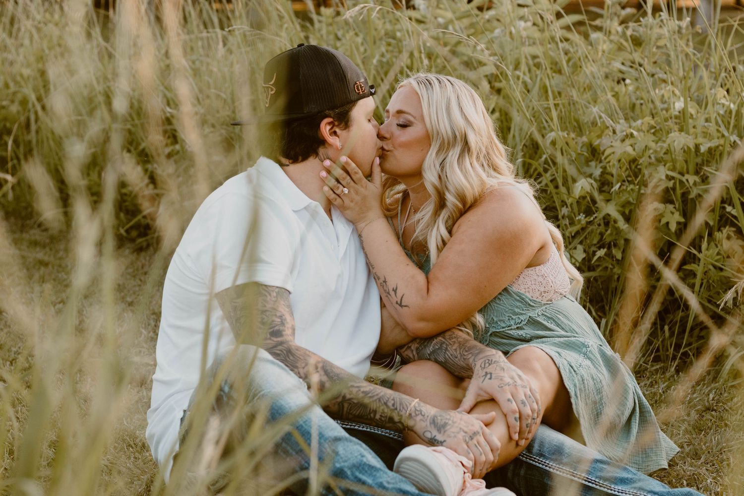 A romantic couple sharing an intimate moment while sitting in tall grass.
