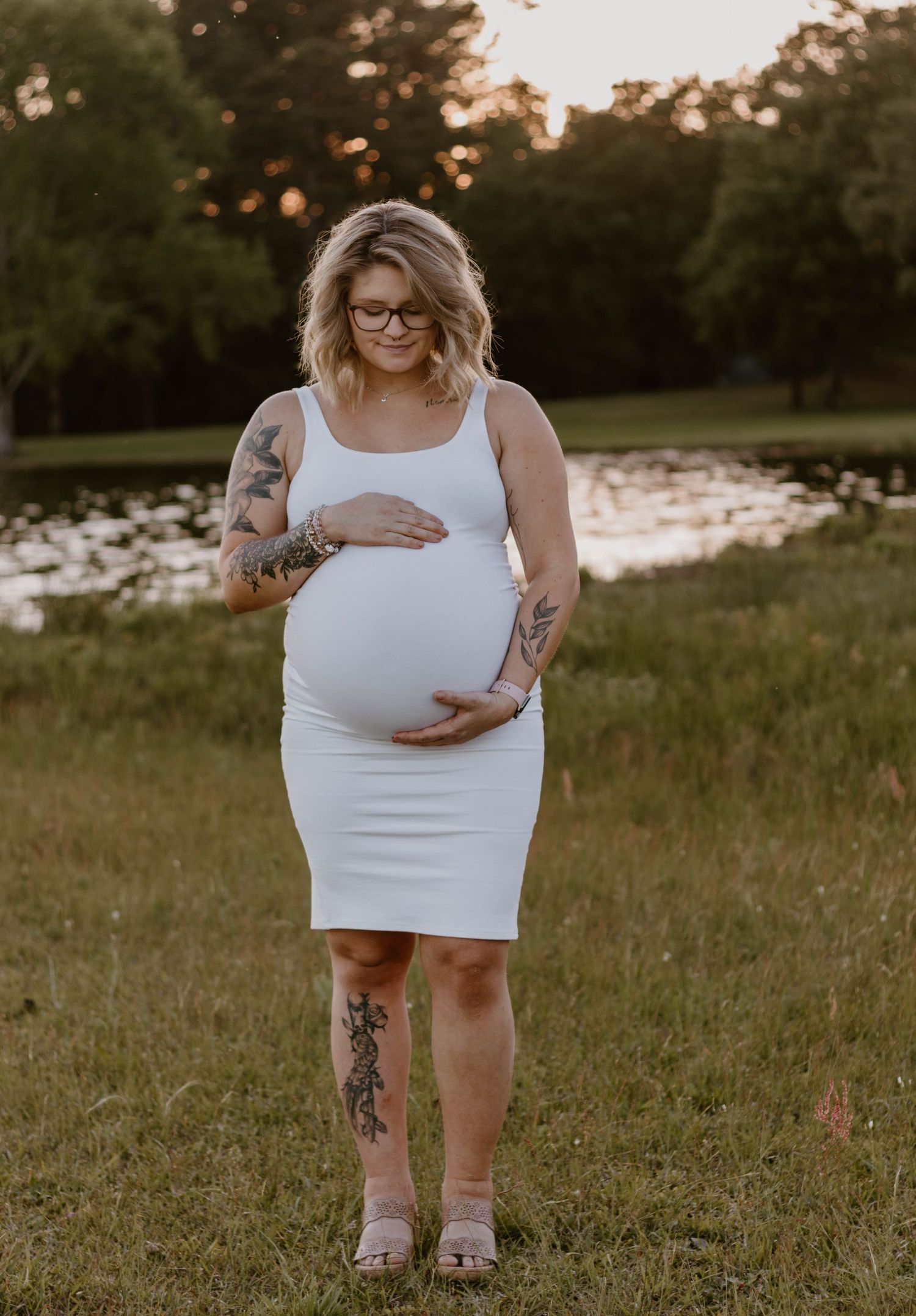 Maternity photography session in natural outdoor setting with sunset backdrop.