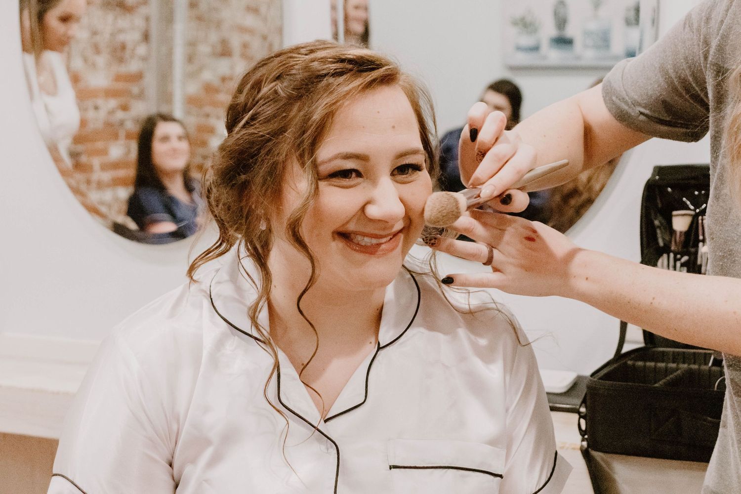 Bridal preparation scene with makeup application and styling in natural light.