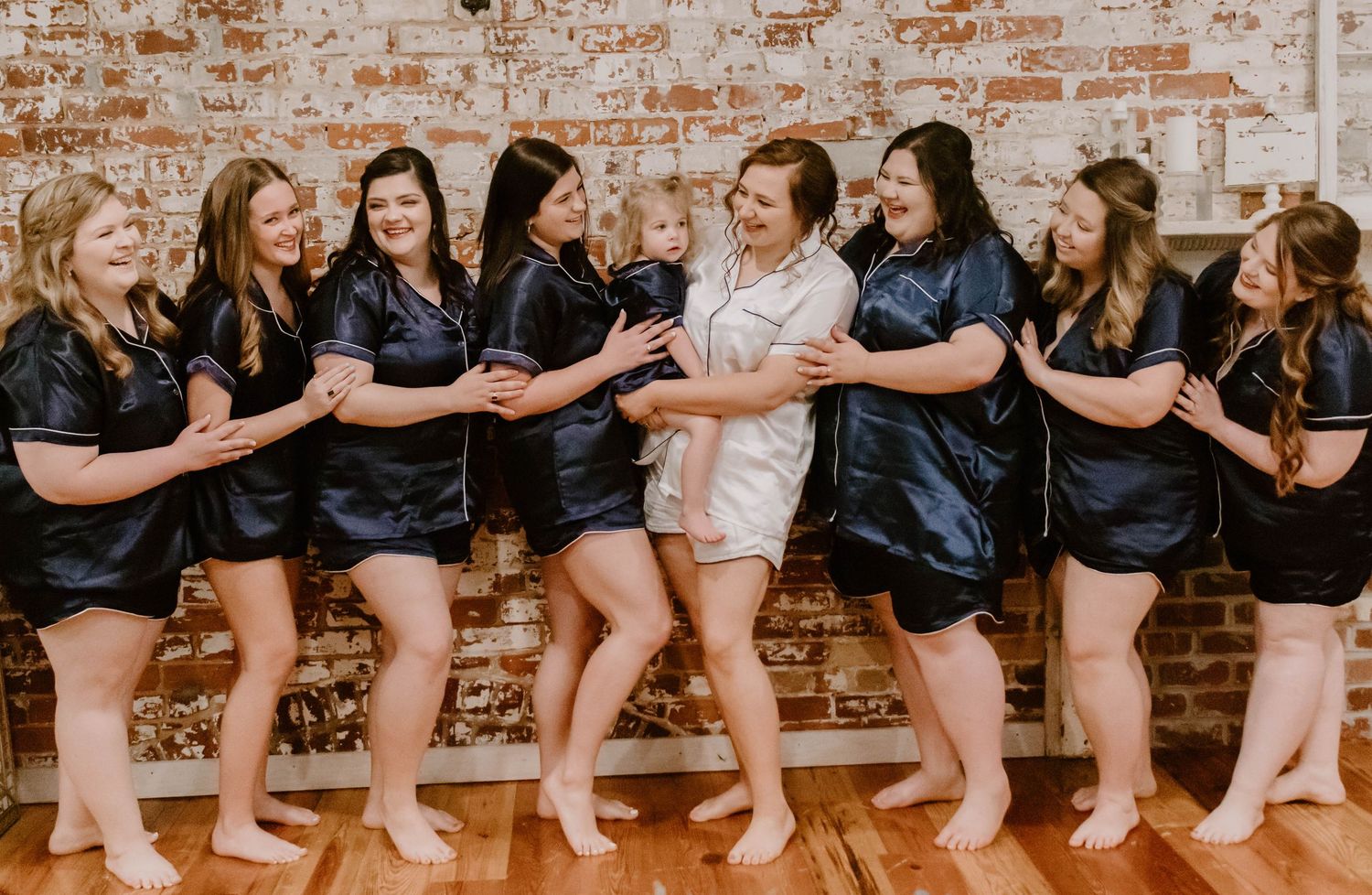 Bridesmaids in matching black robes seated together showing their feet.