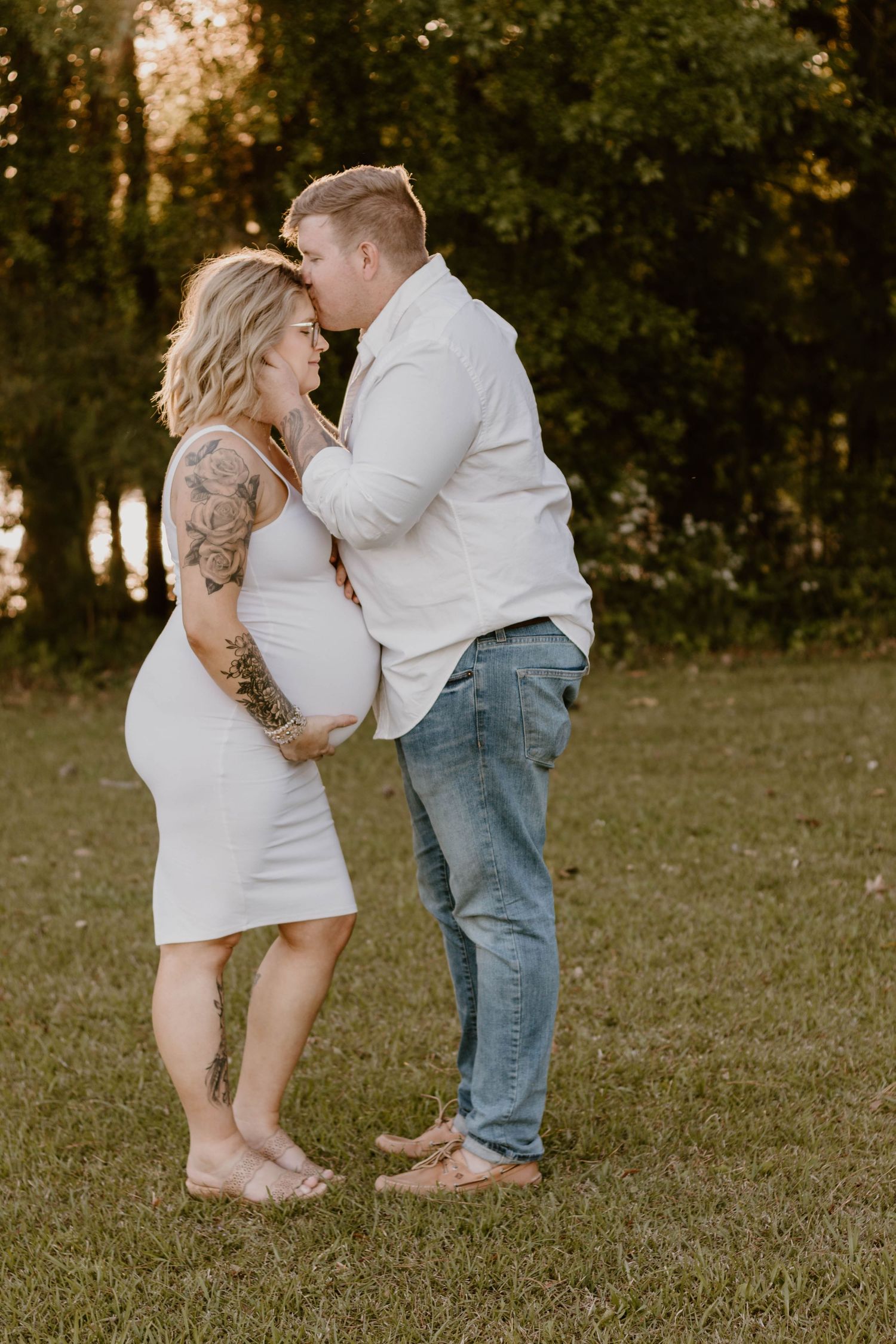 An intimate maternity portrait captures a tender moment between a couple in a natural outdoor setting.
