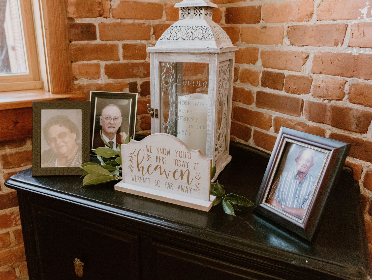 Vintage-style white lanterns and photo frames displayed on dark furniture against brick walls.