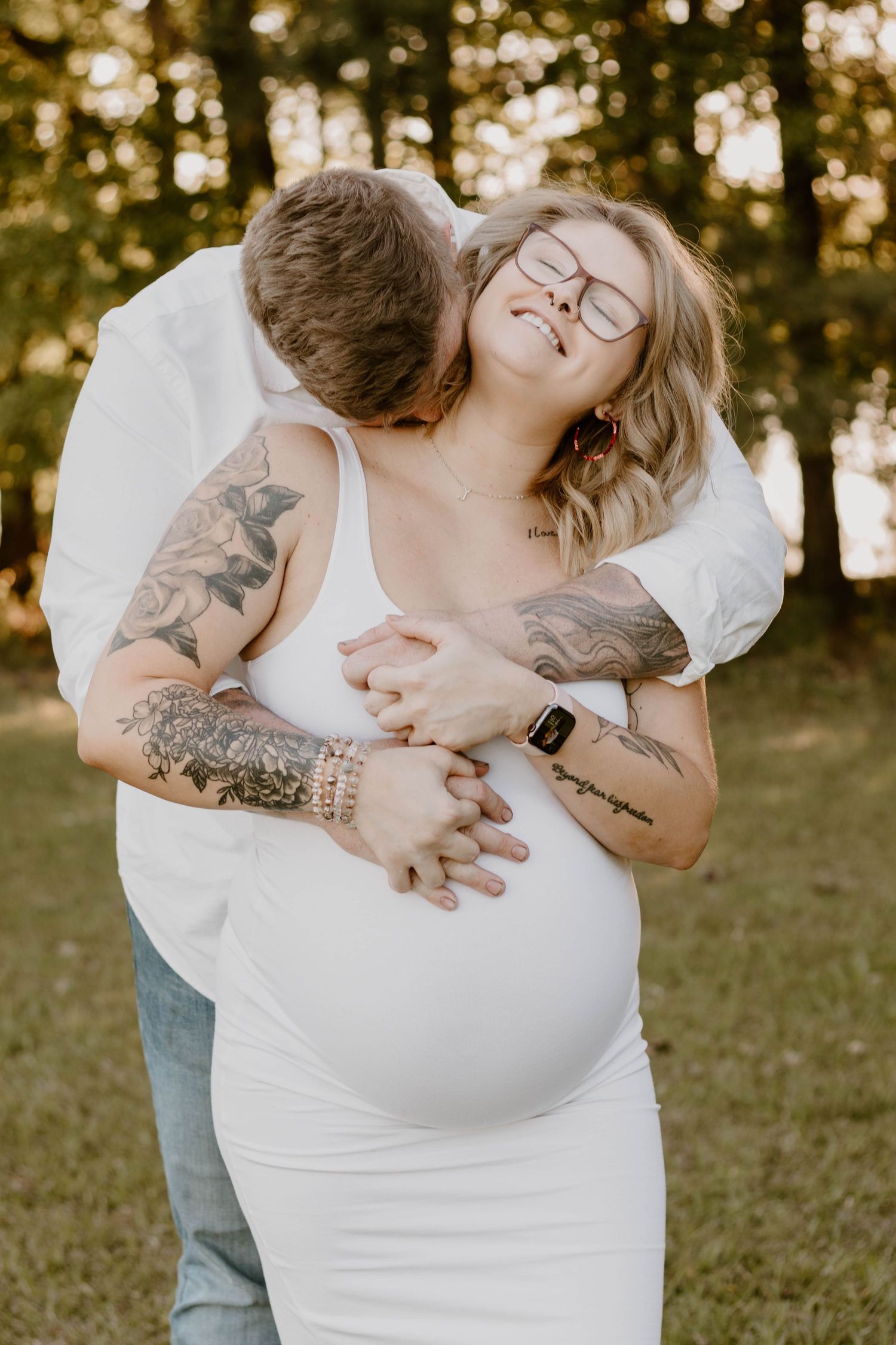 An intimate maternity portrait shows a tender moment between a couple in natural lighting.