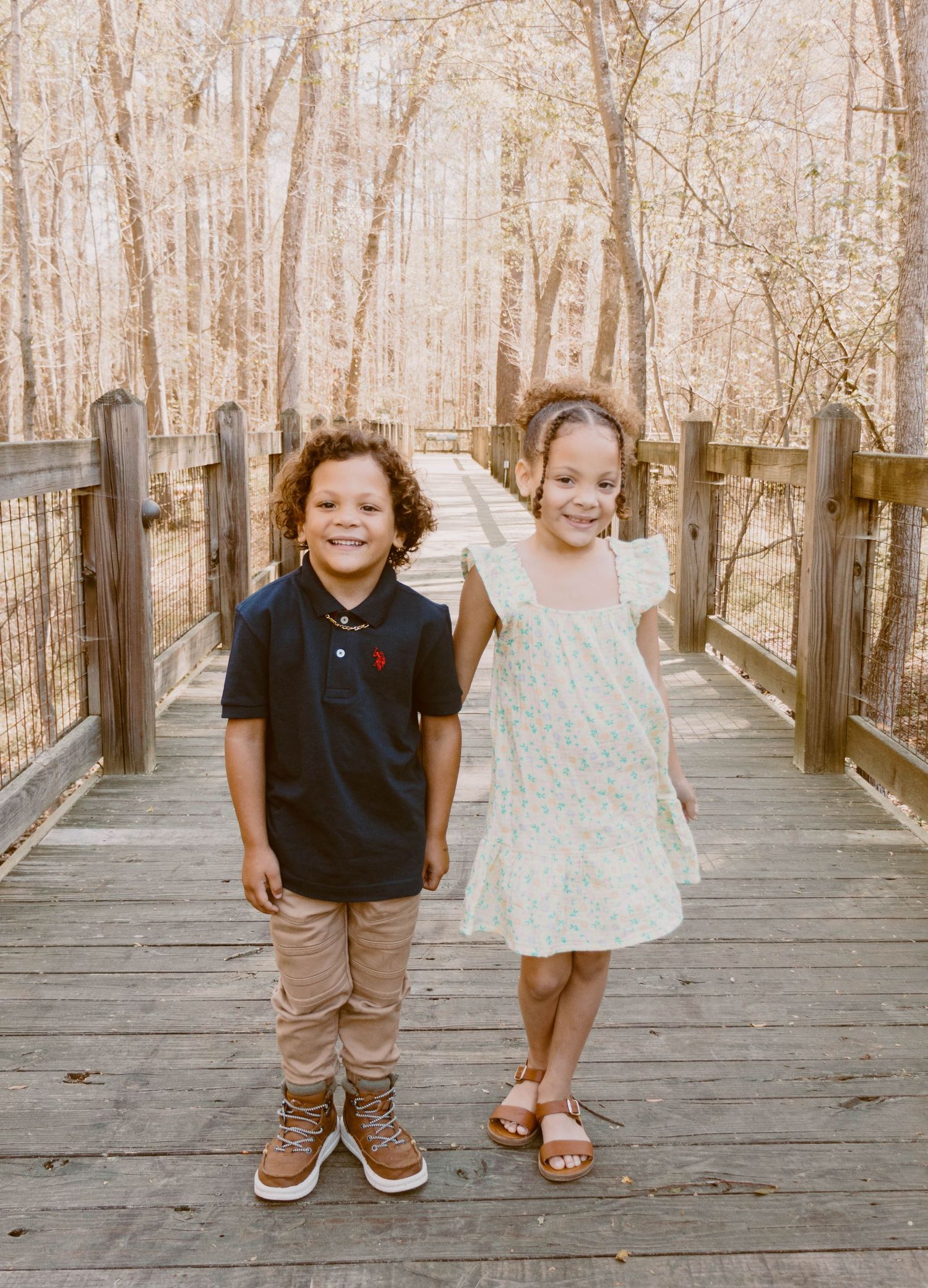 Children's feet and legs photographed on wooden boardwalk in natural setting.