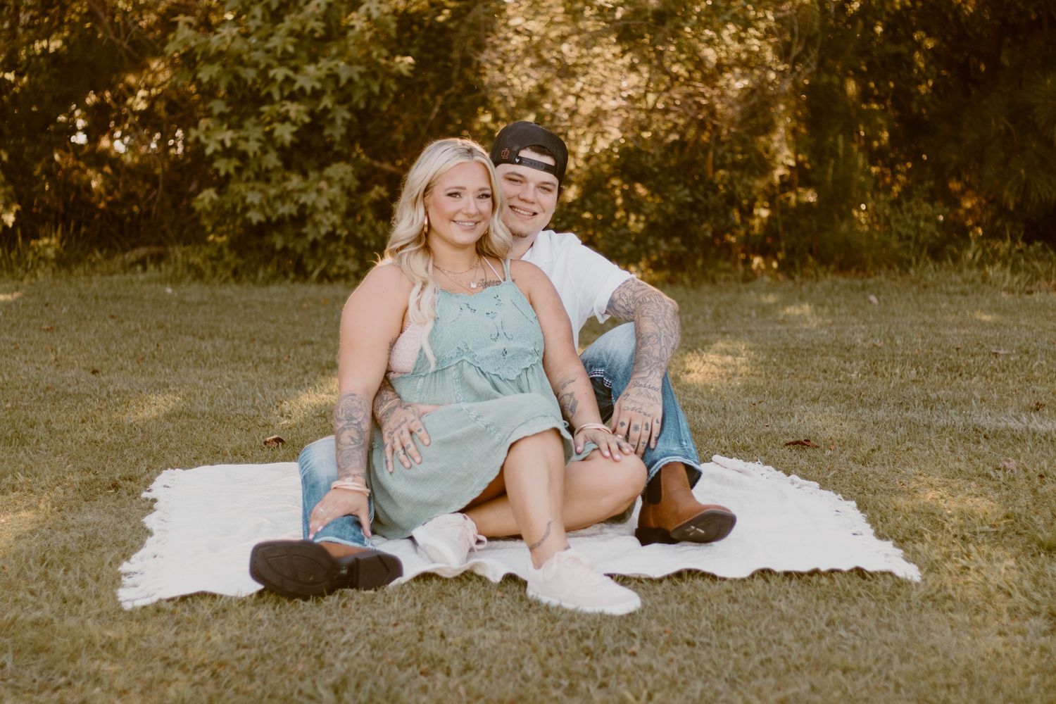 A casual outdoor photo session on a blanket during golden hour.