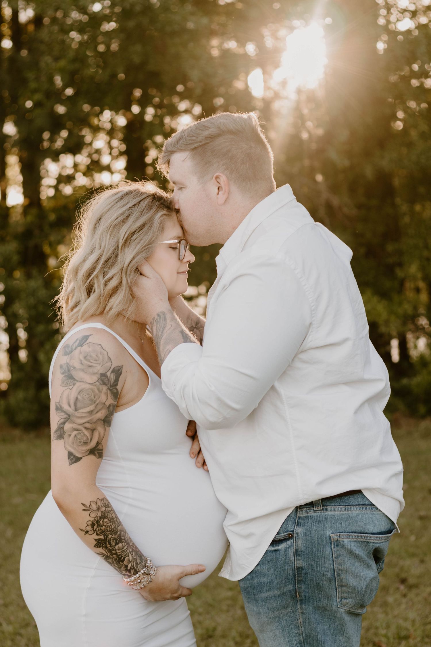 A tender maternity portrait captures an intimate moment between a couple in golden hour lighting.