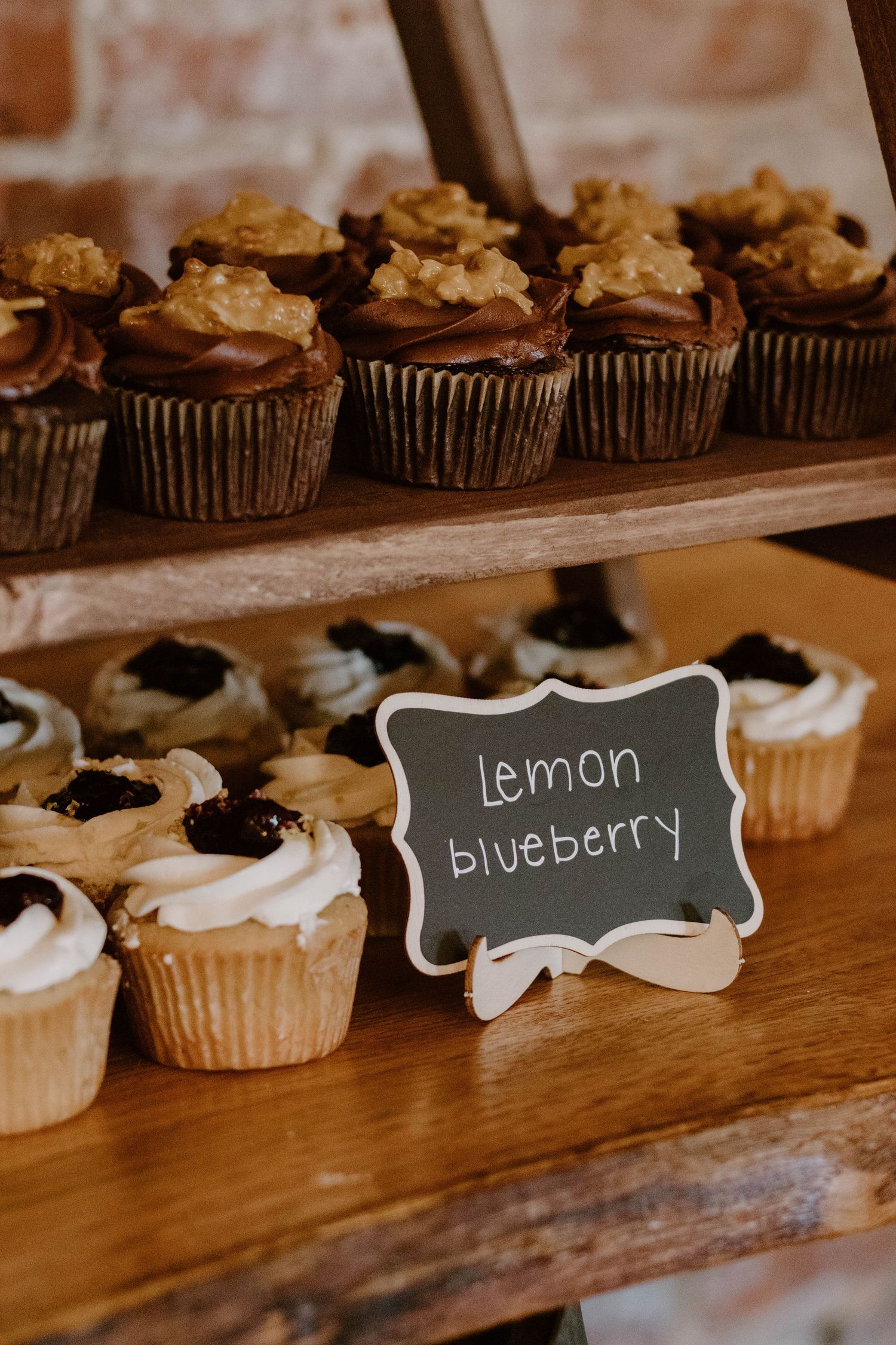 Wedding cupcake display with chalkboard flavor labels including lemon and blueberry.